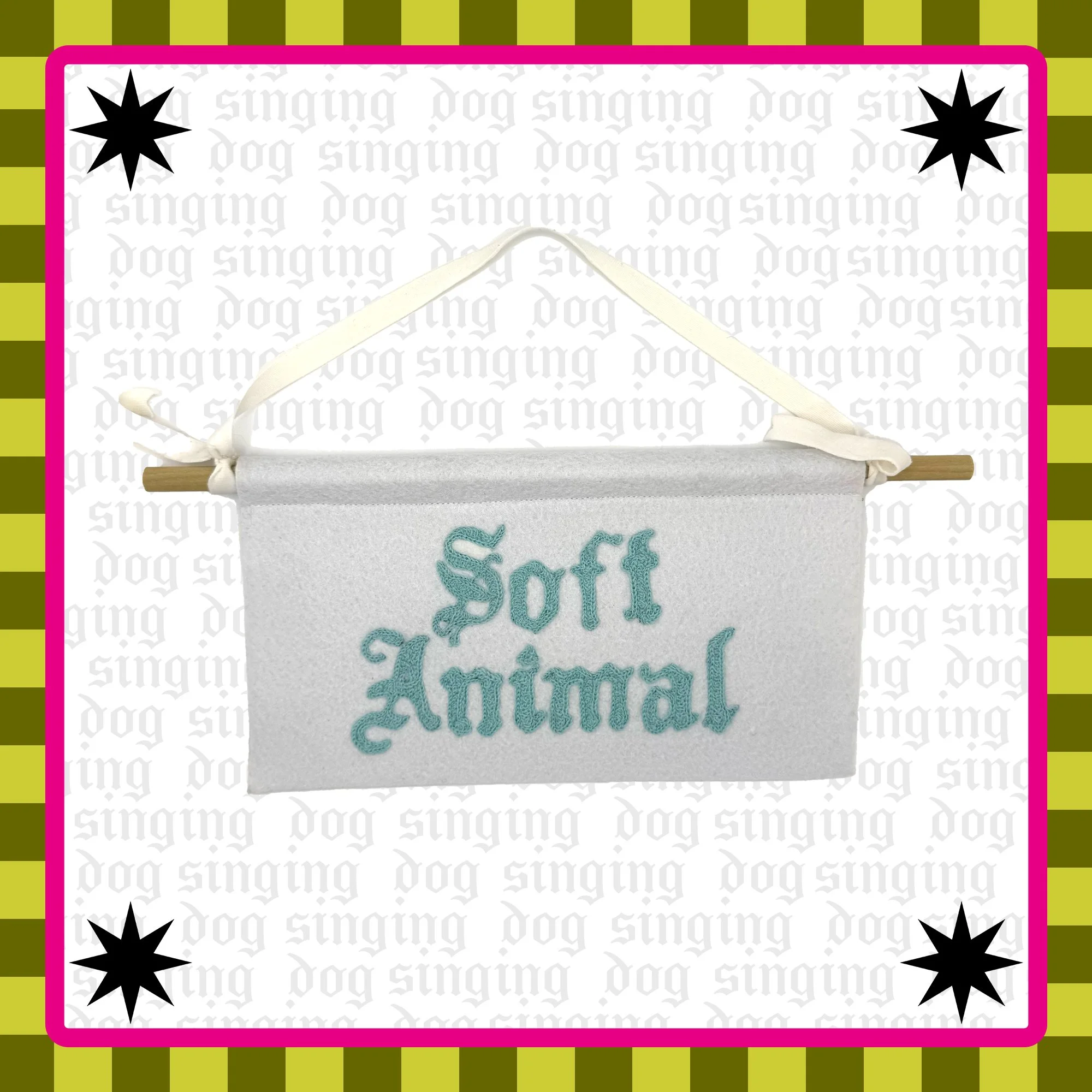 A white felt banner with the words 'soft animal' embroidered in blue thread. 
