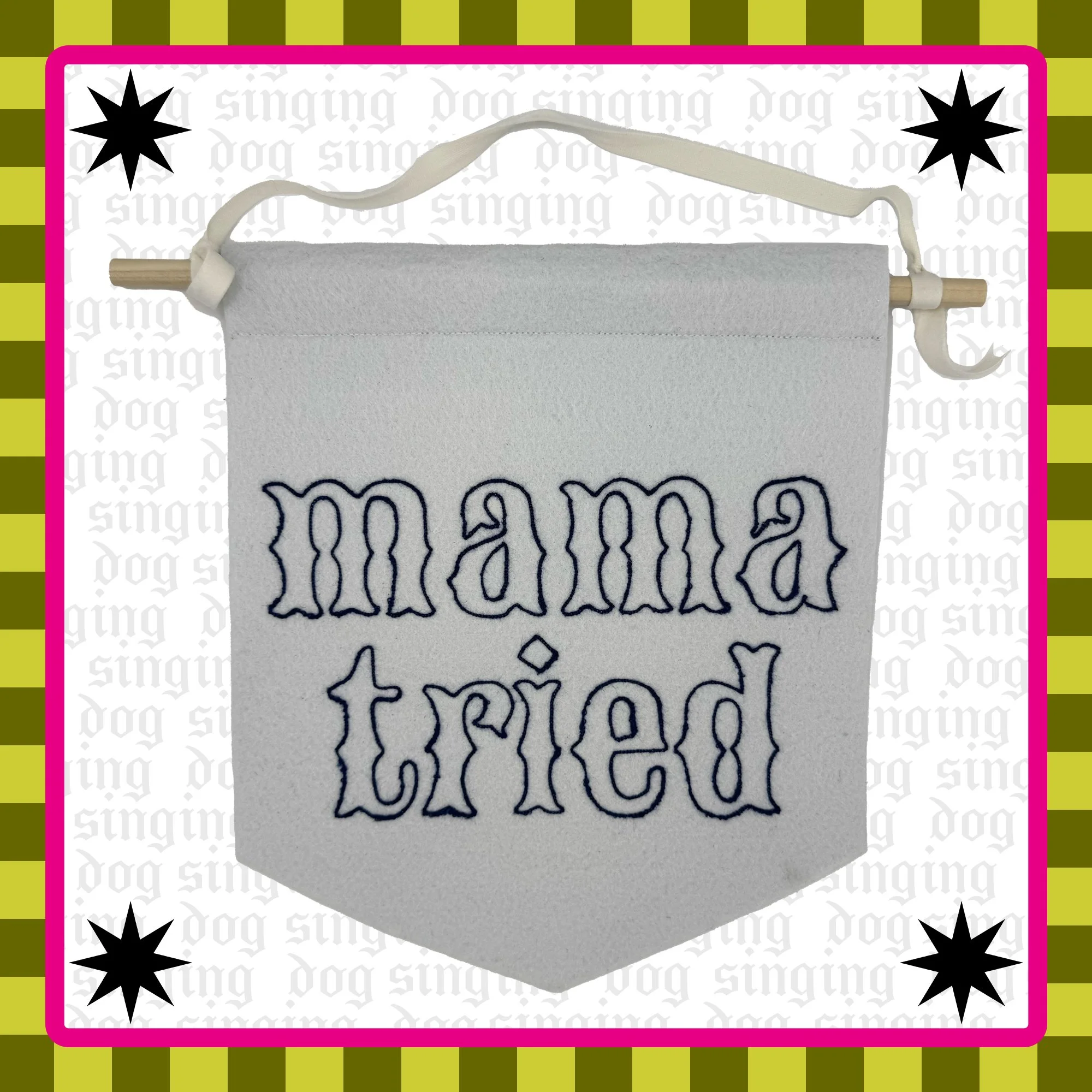 A white felt wall hanging with the lyrics "mama tried" embroidered in blue thread. 
