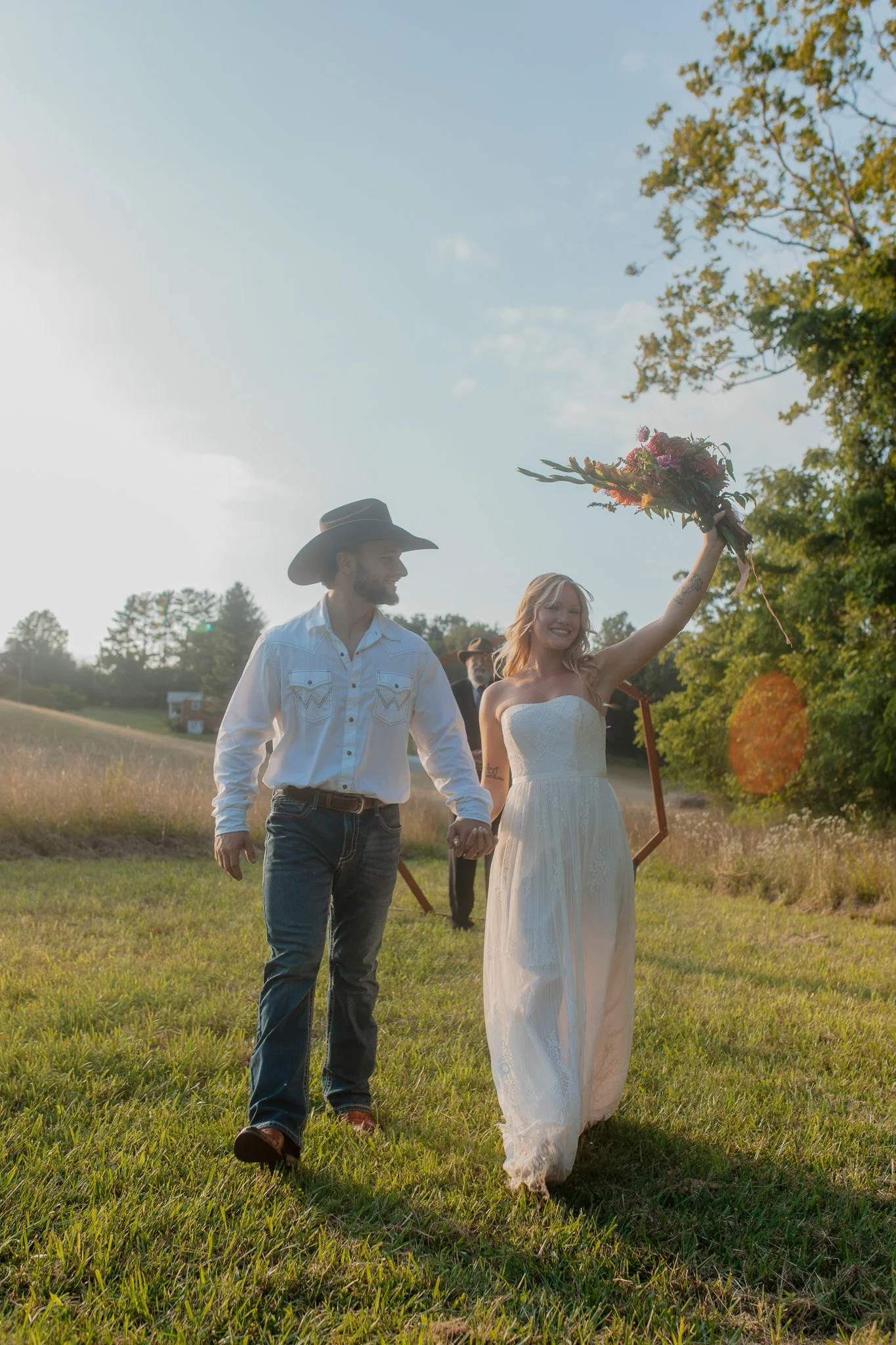 A couple gets married in a meadow ceremony location with fresh local flowers and a circular arch