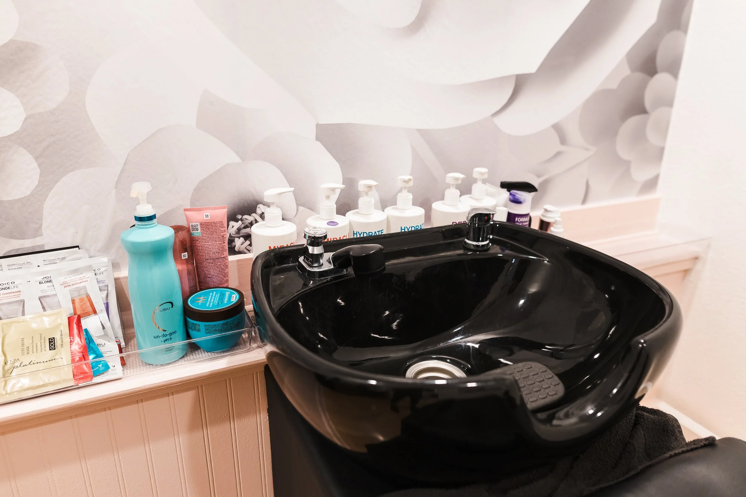 Close-up of a woman's neck and chin, with wet, curly hair and a black earring against a dark background.
