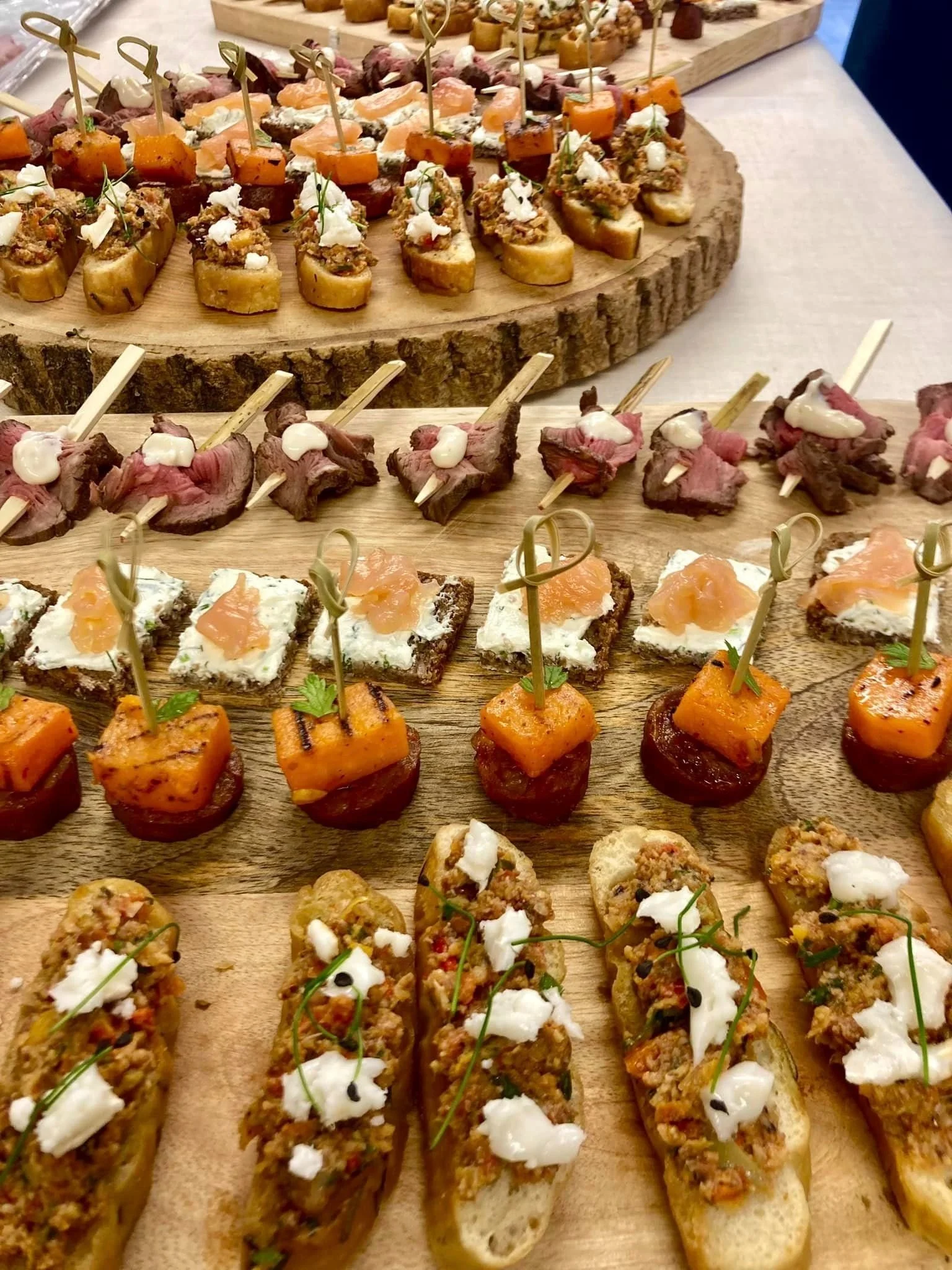 Assorted gourmet appetizers on wooden boards, including sliders, crostinis, and canapés with various toppings.