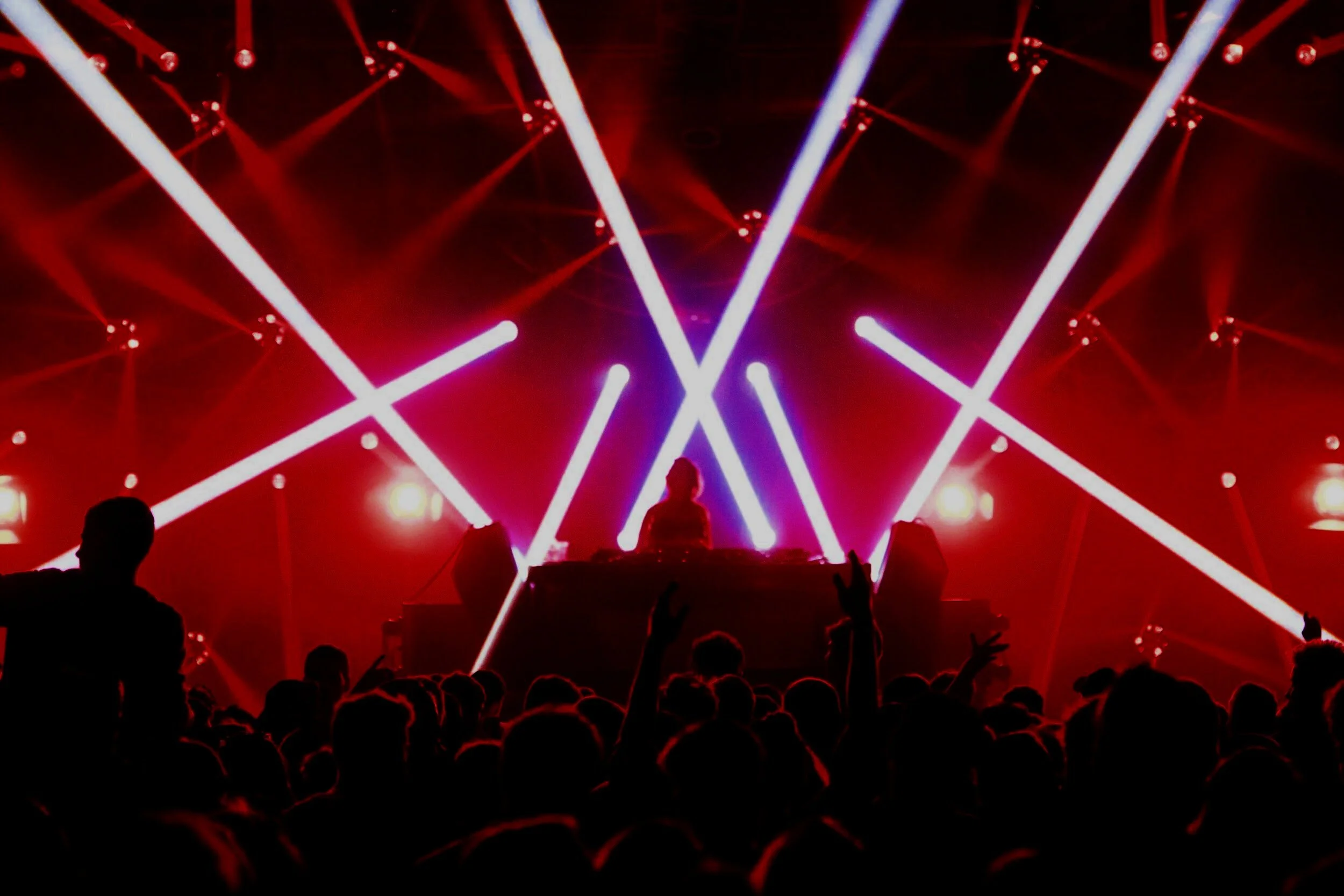 DJ playing to crowd on dancefloor at nightclub with purple lasers