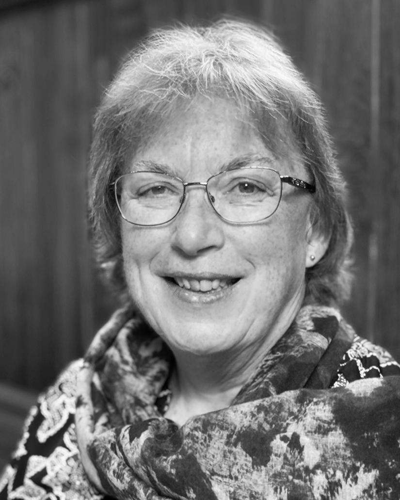 Sheelagh Aston: Black and white portrait of a smiling woman with short hair, wearing a patterned scarf.