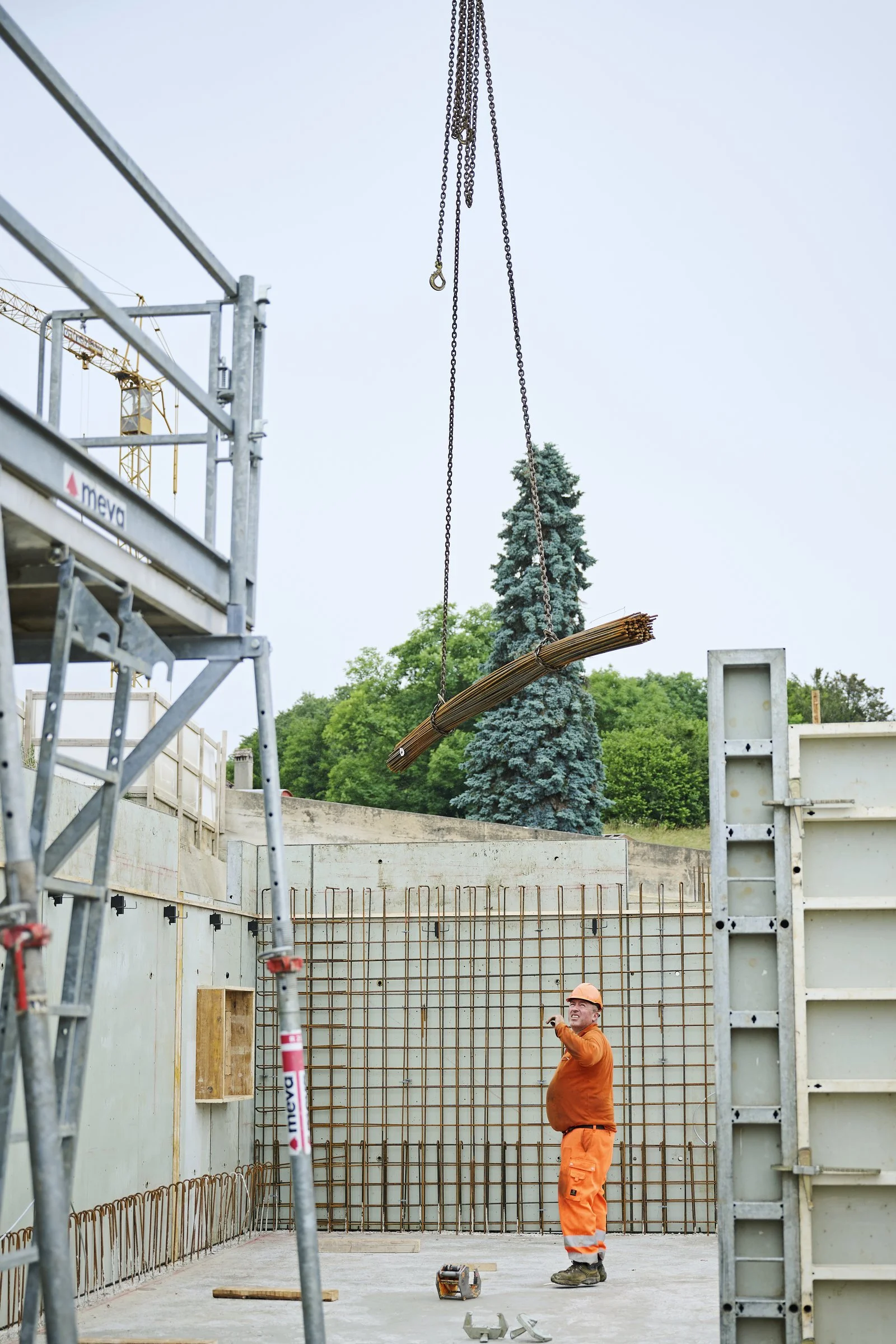 Levage d'un fagot d'armatures par une grue sur un chantier, suivi de chantier à Neuchâtel