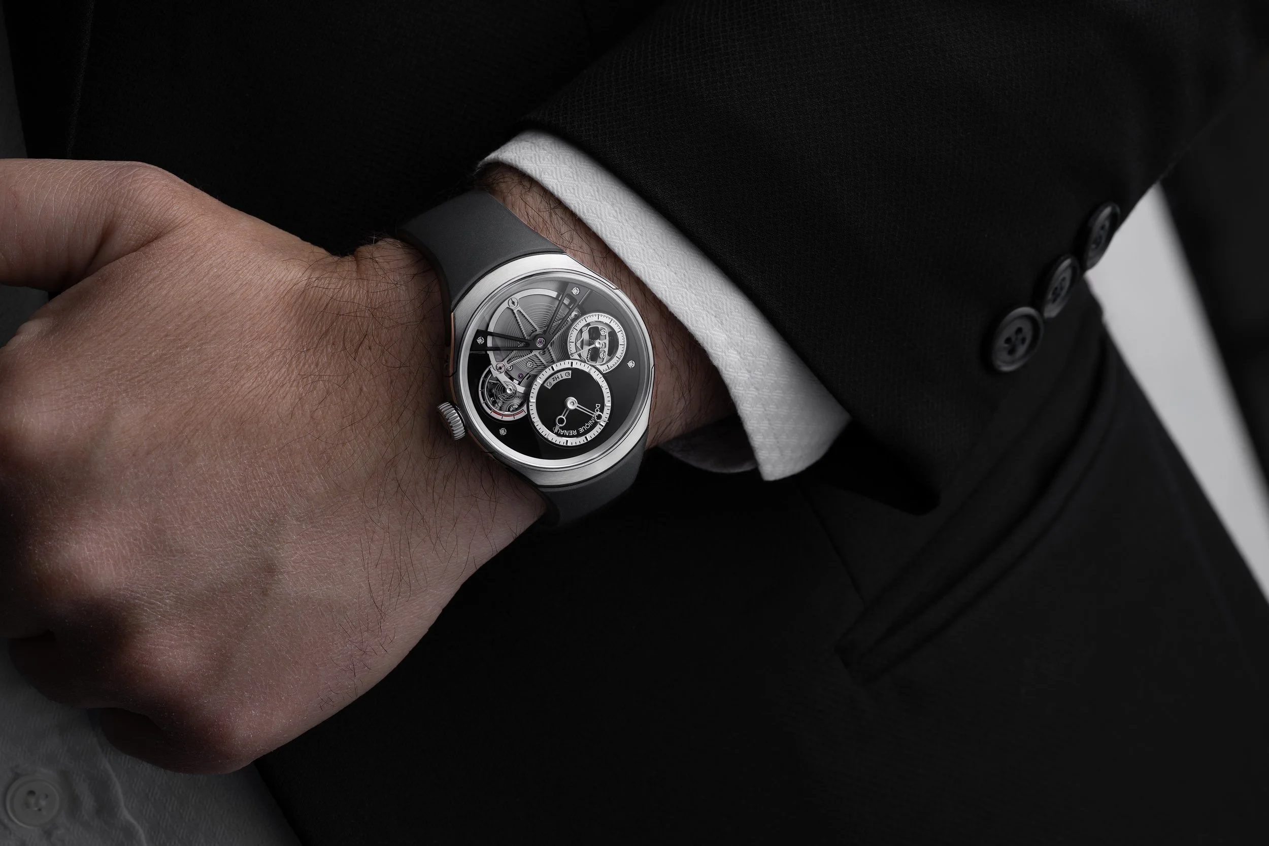 Montre Dominique Renaud au poignet sous une veste de costume, photographie lifestyle horlogère
