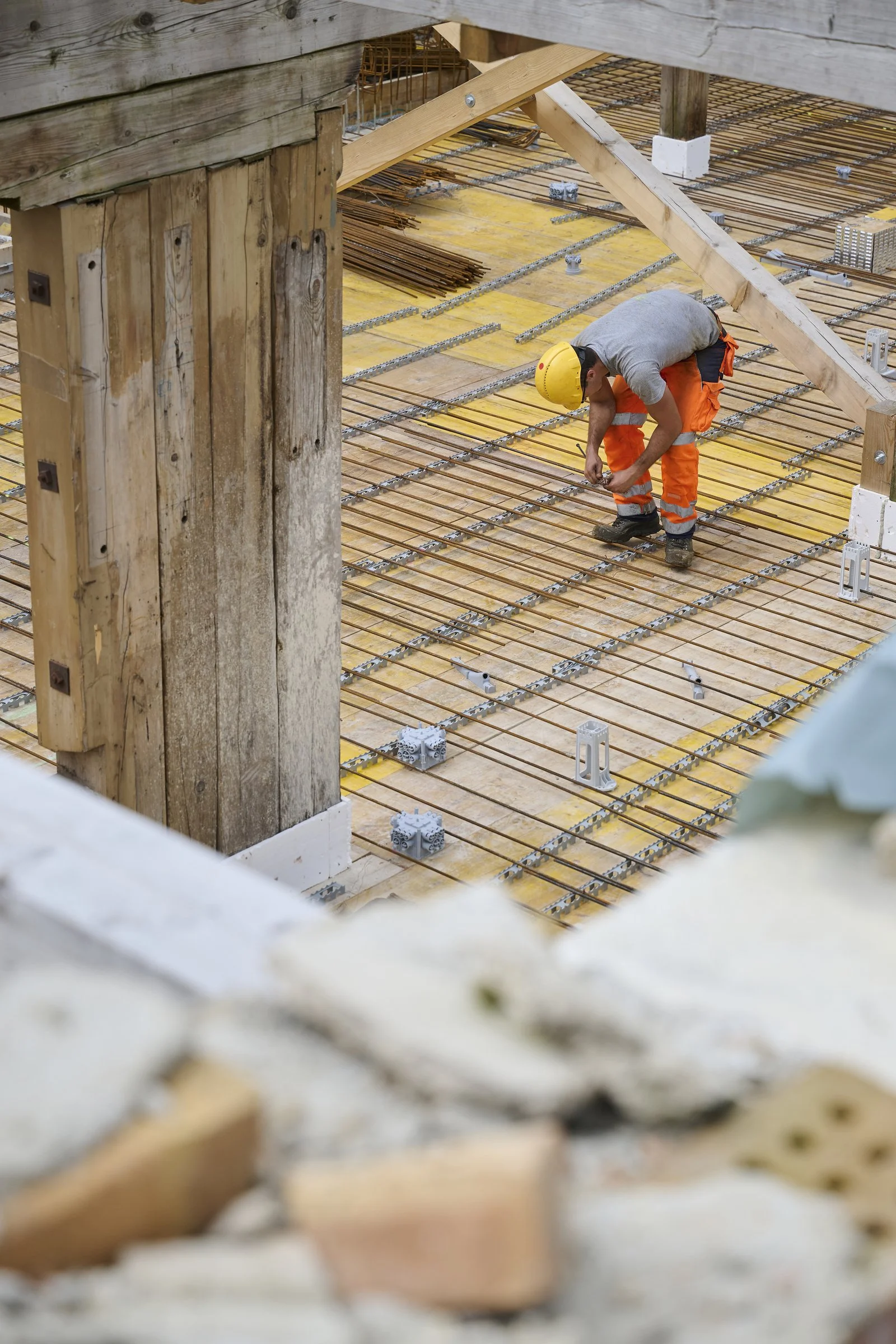 Ouvrier en tenue orange posant le ferraillage d'une dalle, reportage de chantier à Neuchâtel