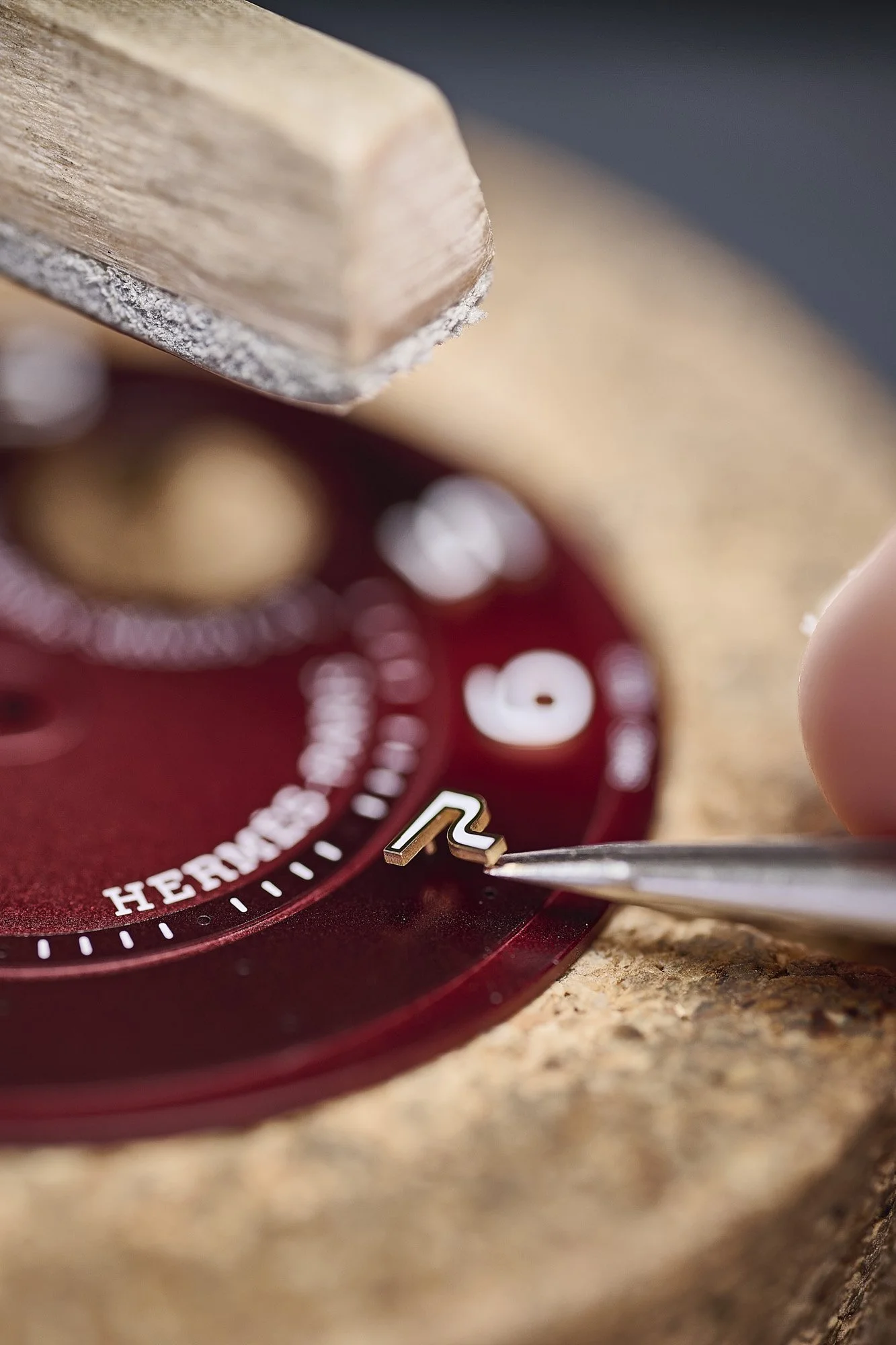 Pose d'un index sur un cadran Hermès rouge, métier d'art et savoir-faire horloger, luxury watch photography