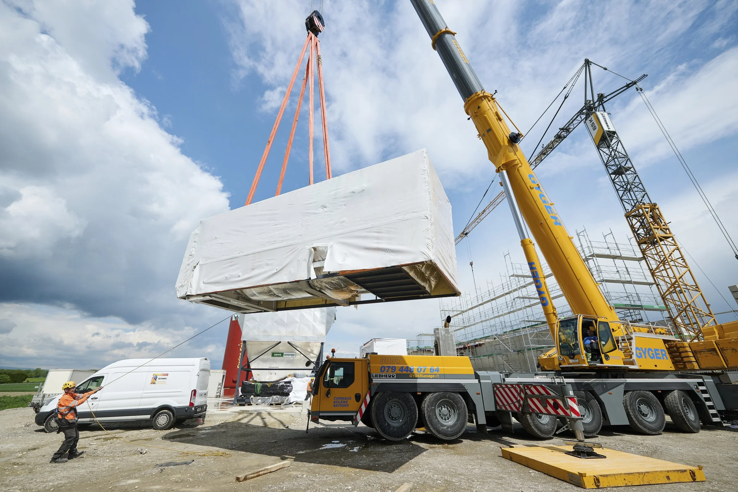 Grue mobile levant un module préfabriqué sur un chantier, suivi de chantier à Neuchâtel