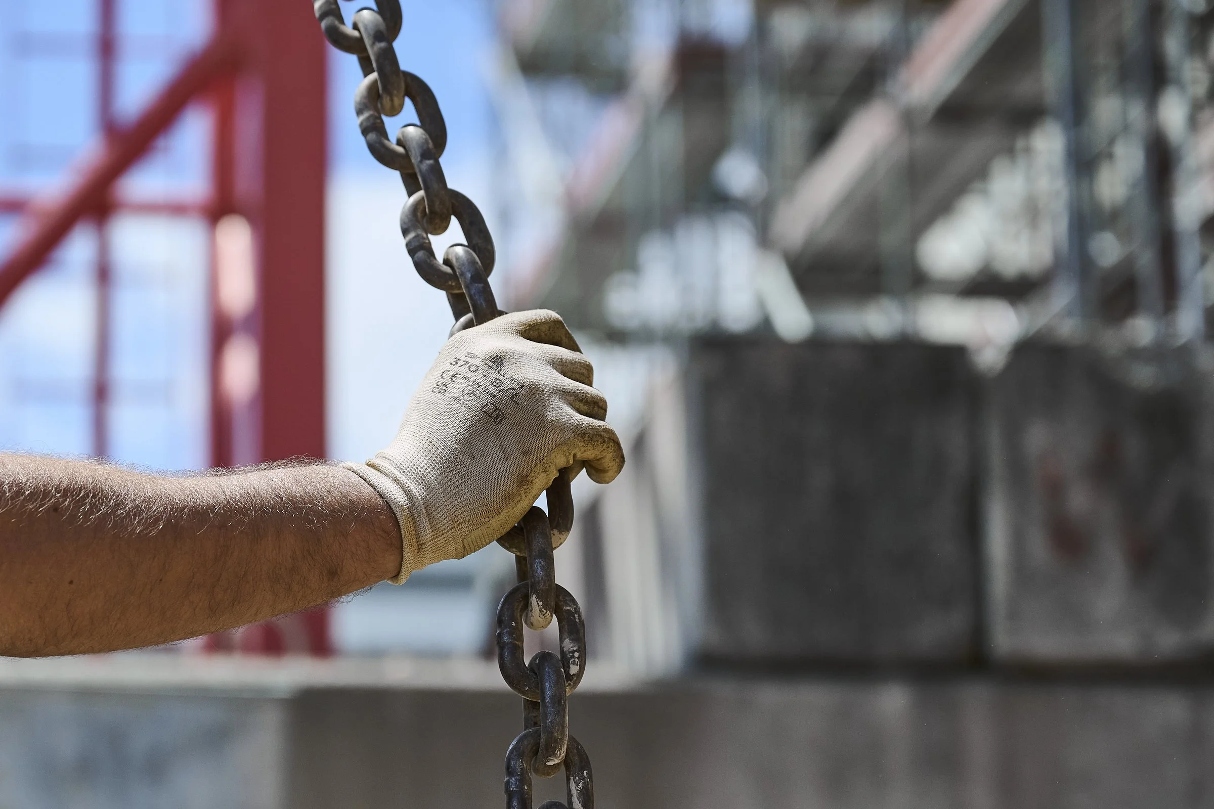 Main gantée tenant une chaîne de levage sur un chantier, photographie de détail de chantier à Neuchâtel