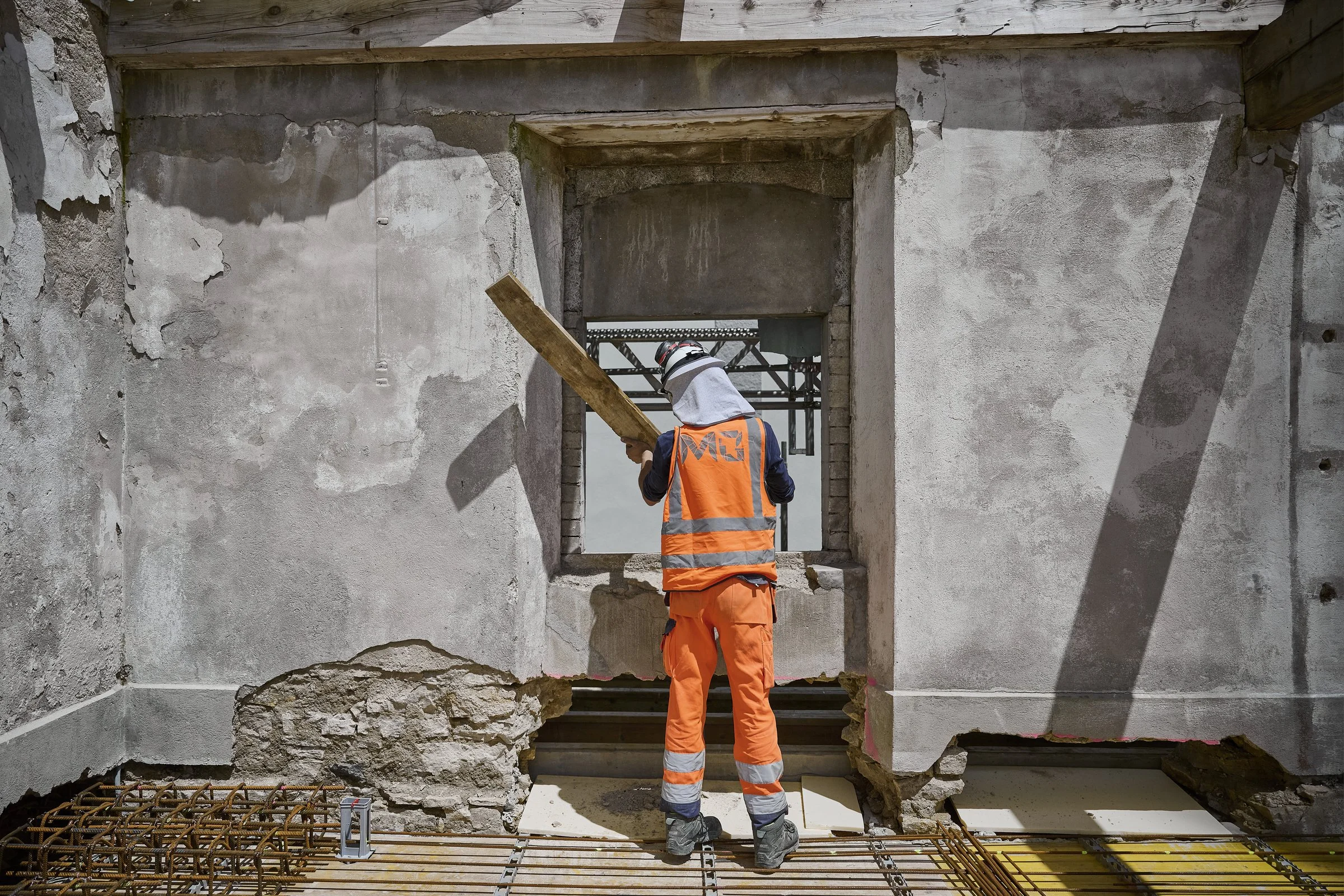 Ouvrier en tenue orange sur un chantier de rénovation, reportage de chantier à Neuchâtel