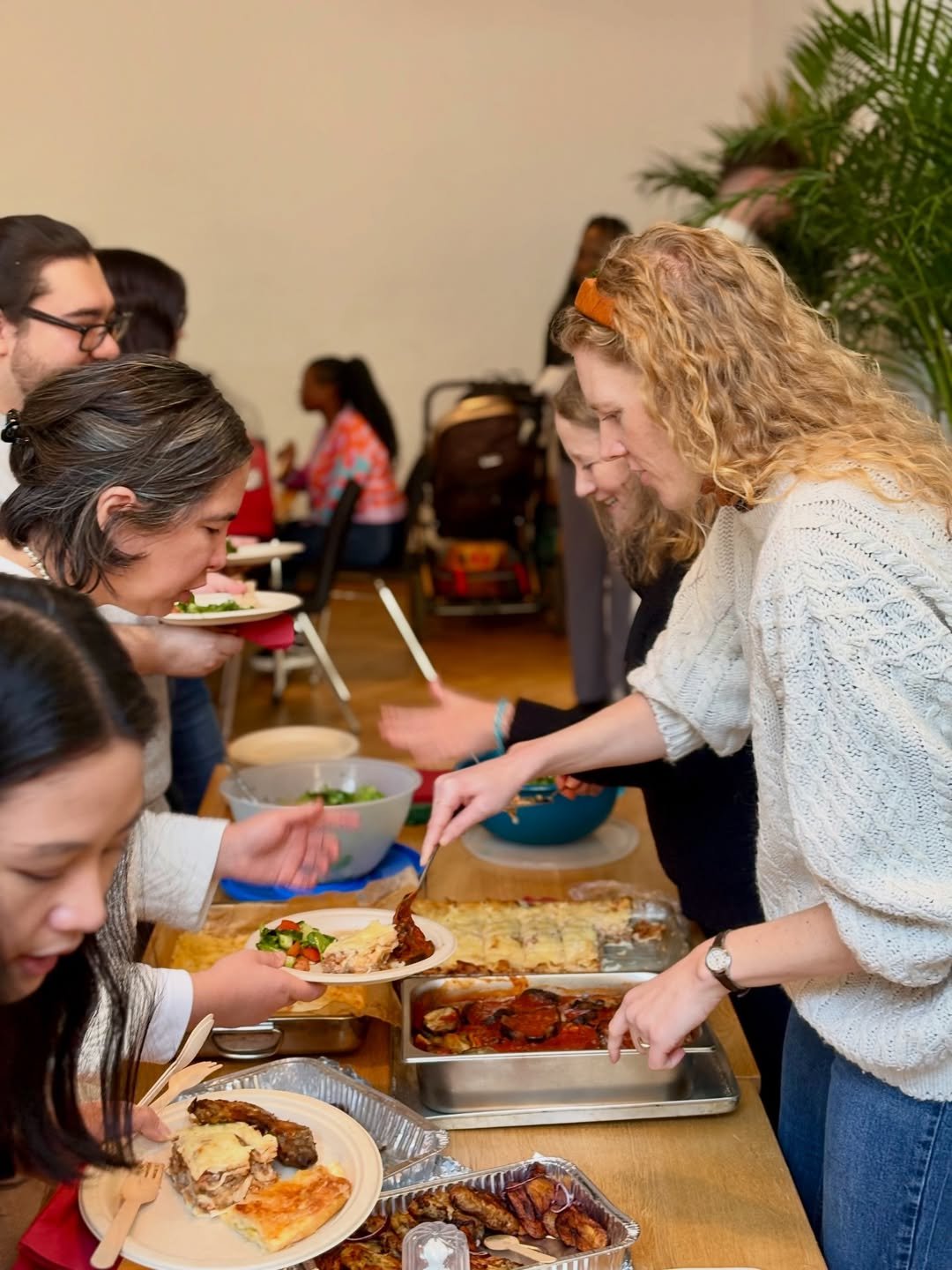 People serving pizza and salads at a community buffet after service at this international church Berlin in the Prenzlauer Berg neighborhood.