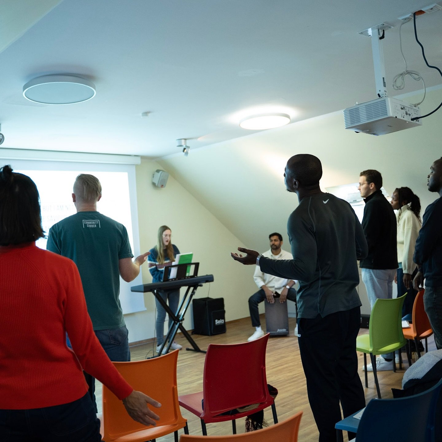 Church members singing and praying during our autumn retreat, with a woman leading worship at a keyboard for our international church Berlin community.
