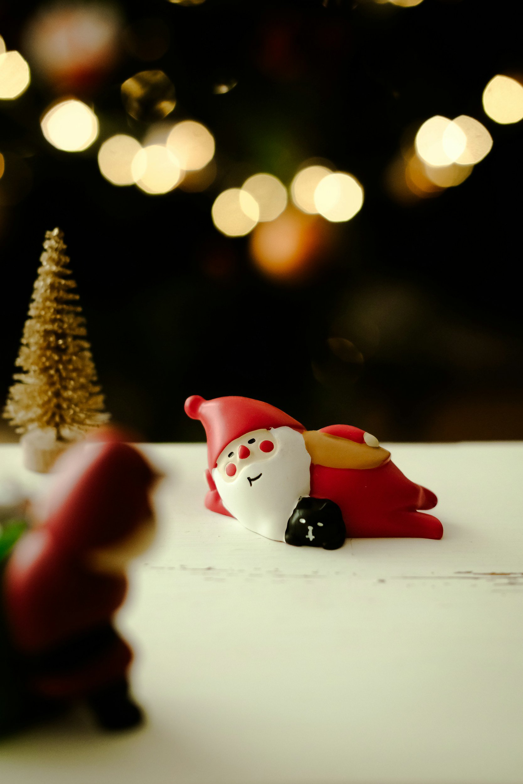 A toy Santa Claus Relaxes on a white windowsill surrounded by other festive toys