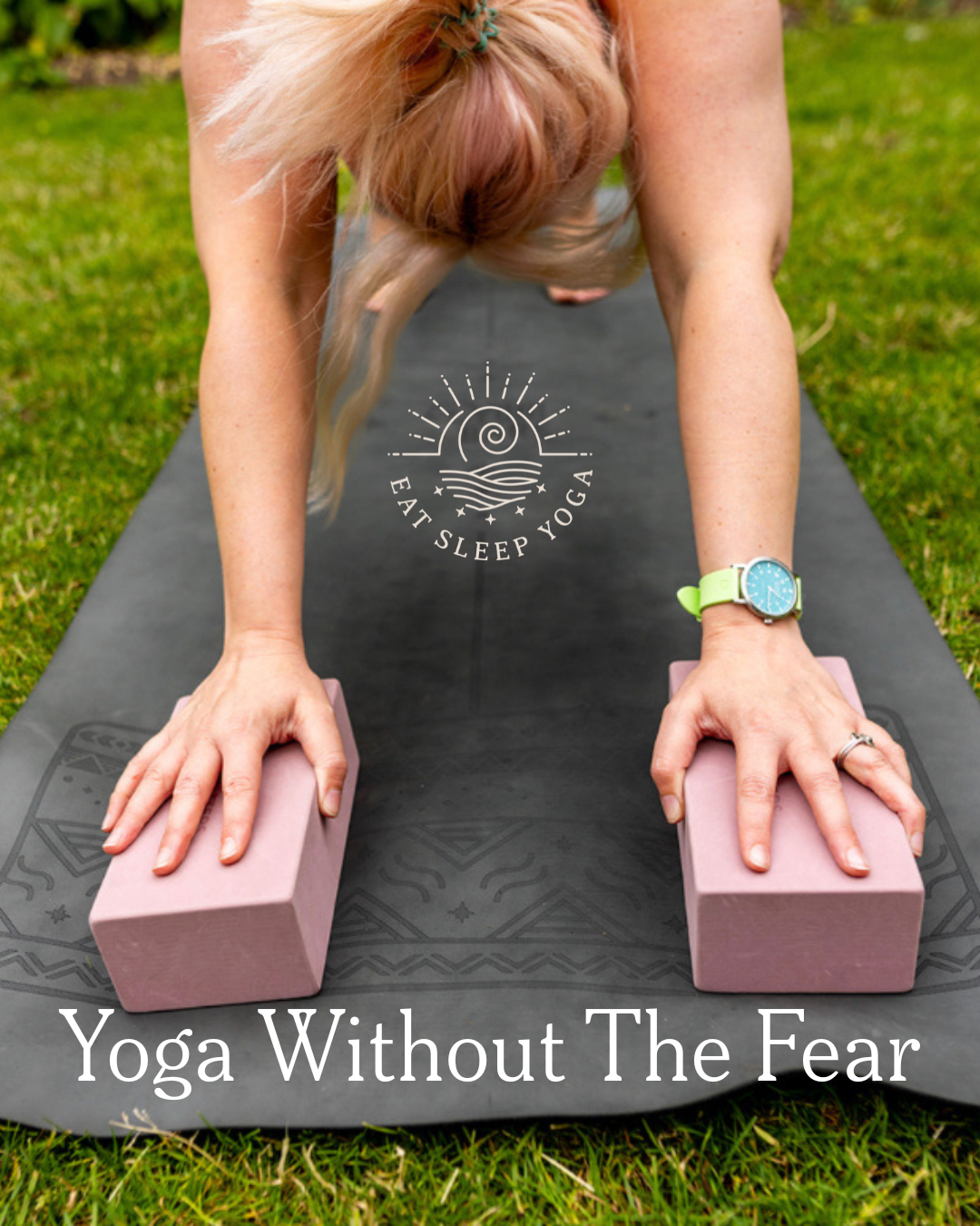 A person practicing yoga outdoors on a black mat, in a downward dog pose, with two pink yoga blocks under her hands. The image has the text "Yoga Without The Fear" and a logo with a sun, waves, and the words "Eat Sleep Yoga".