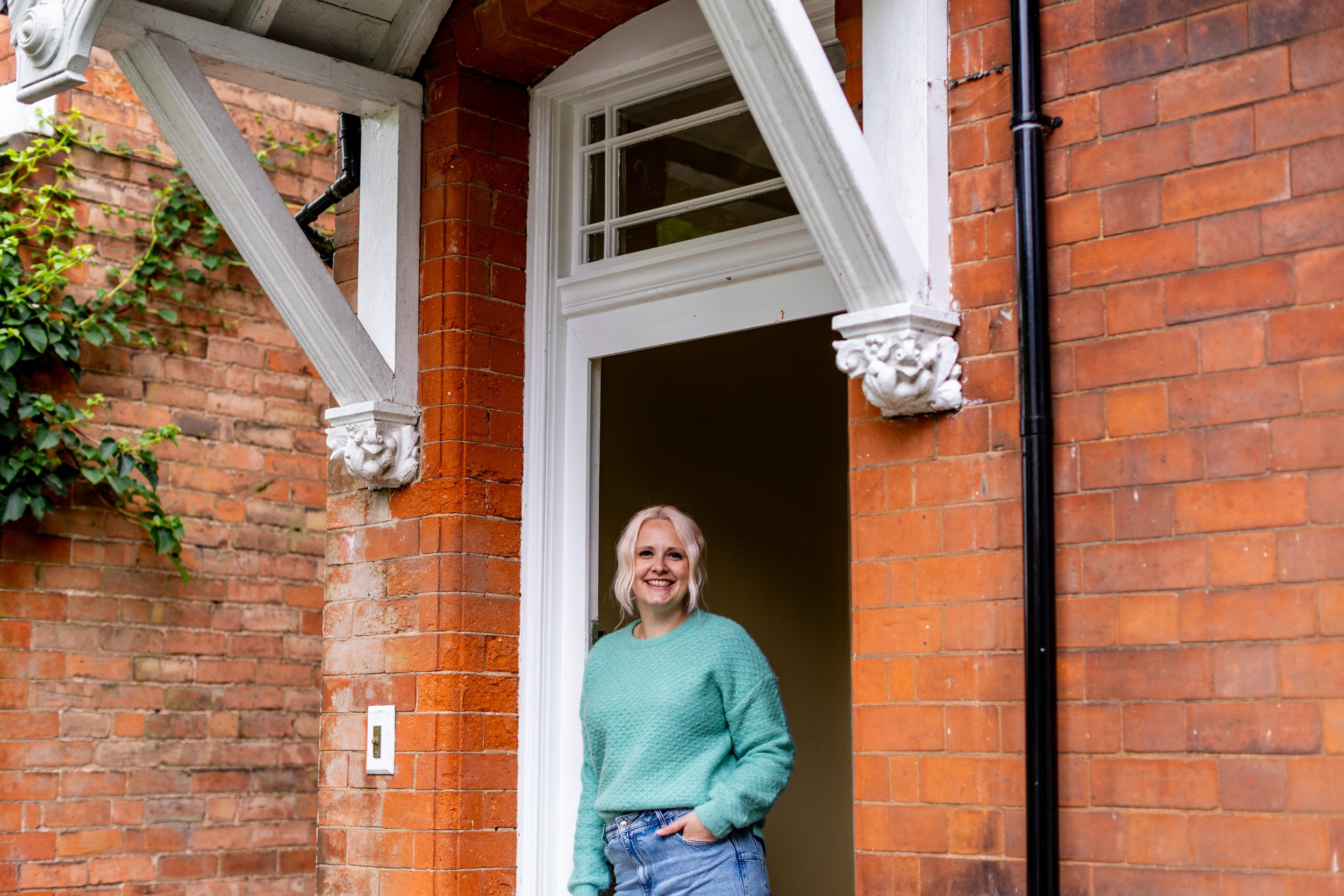 Ruth is standing at a doorway welcoming trainee Yoga Teachers to the course