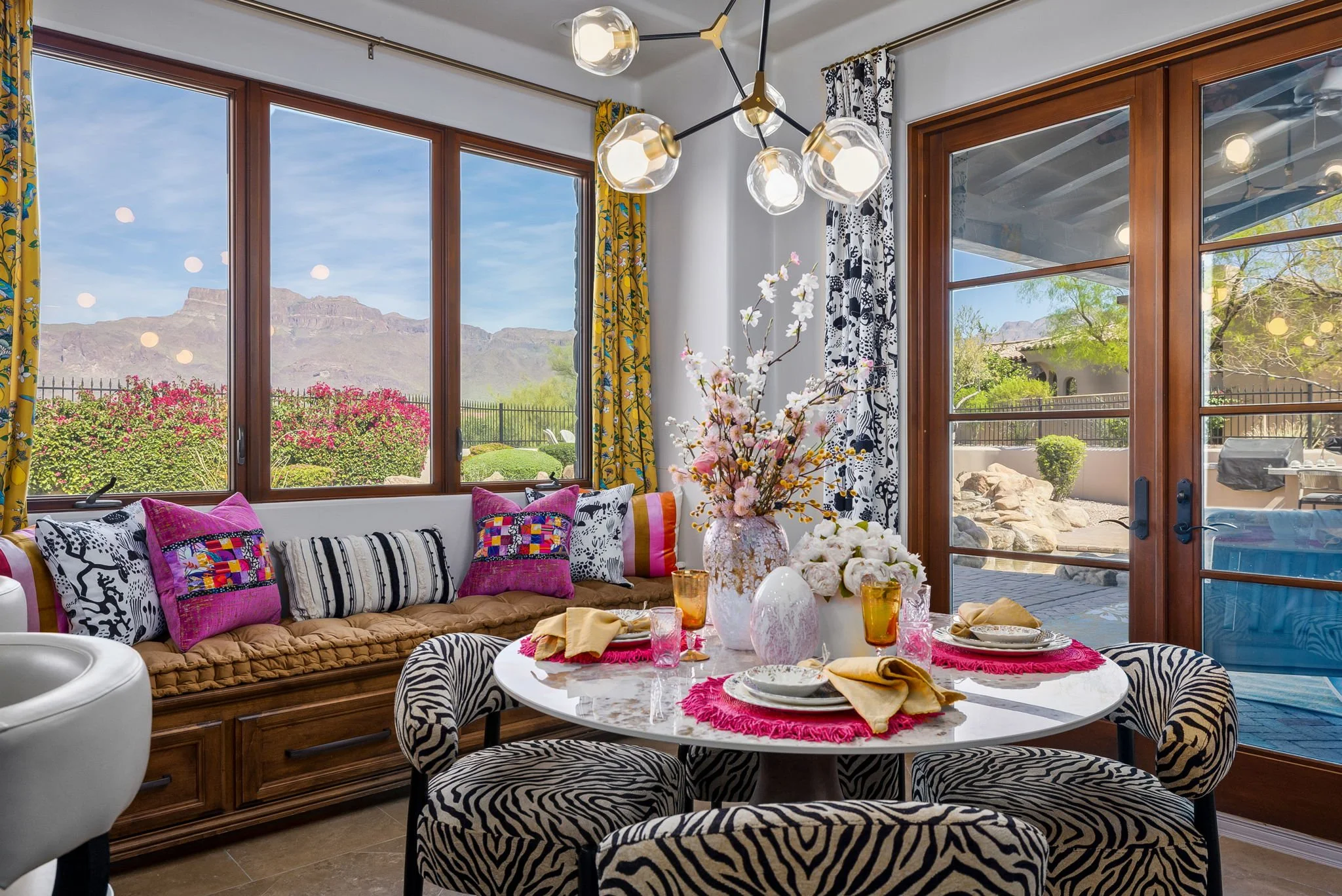 Vibrant breakfast nook with zebra print chairs and mountain views in Superstition Mountain Golf Community, redesigned by Red Carrot Design in Gold Canyon, AZ.