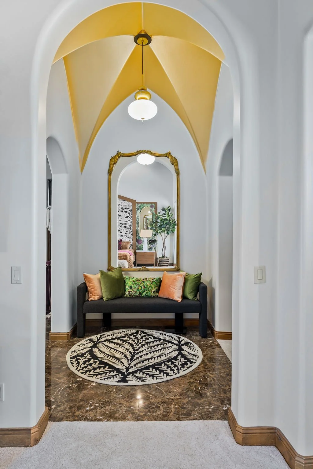 Passage hallway with a yellow groined vault ceiling, arched gold mirror, and fern print rug in Superstition Mountain, Gold Canyon, AZ.