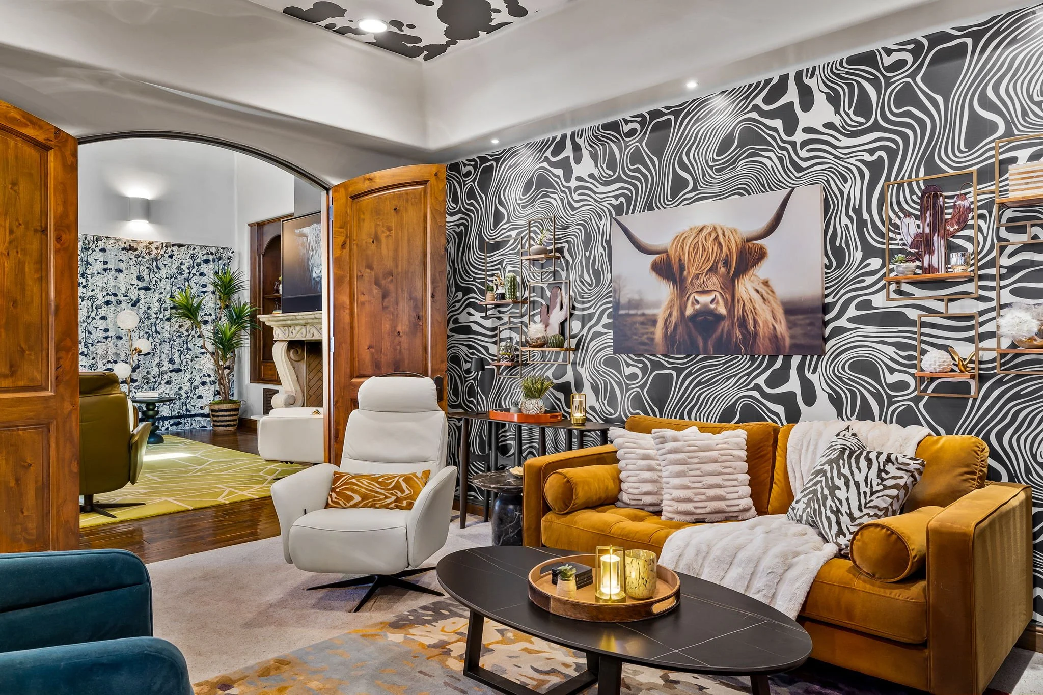 Luxury lounge featuring a mustard velvet sofa, highland cow artwork, and black-and-white marbled wallpaper by Red Carrot Design in Gold Canyon, AZ.