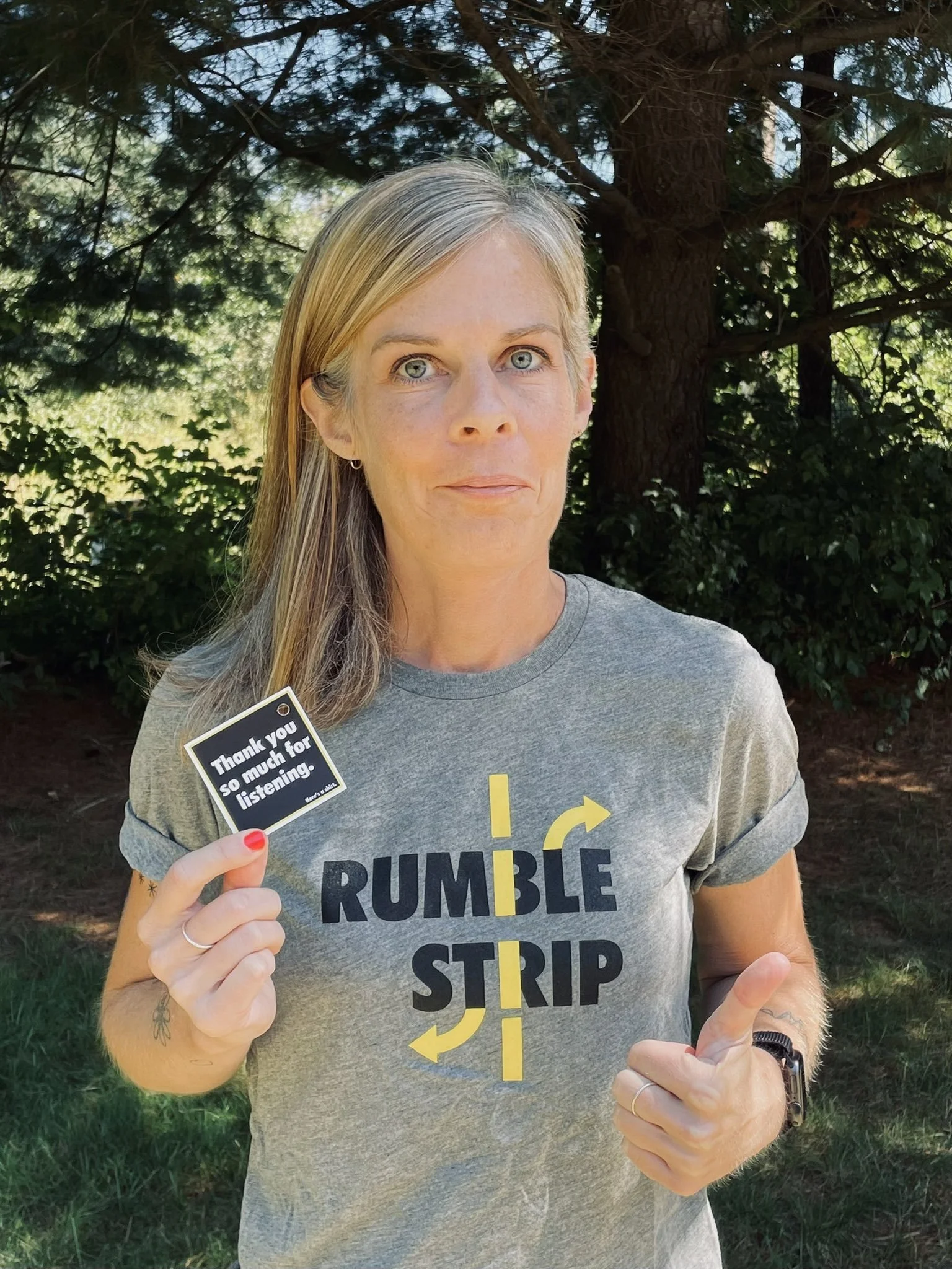 Woman wearing Rumble Strip t-shirt and holding Rumble Strip sticker