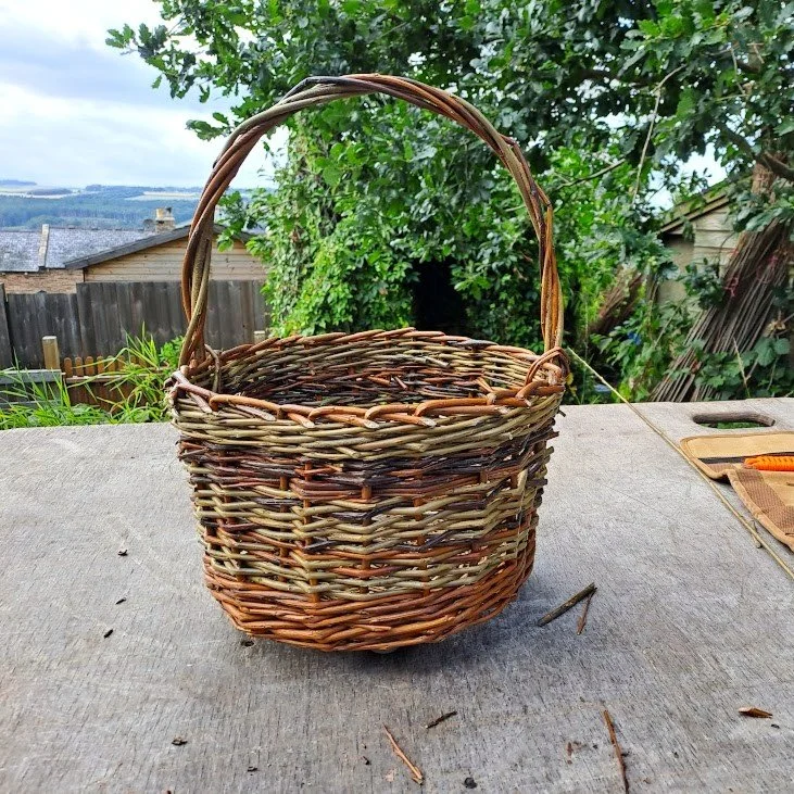 Empty woven wicker basket on a wooden surface outdoors.
