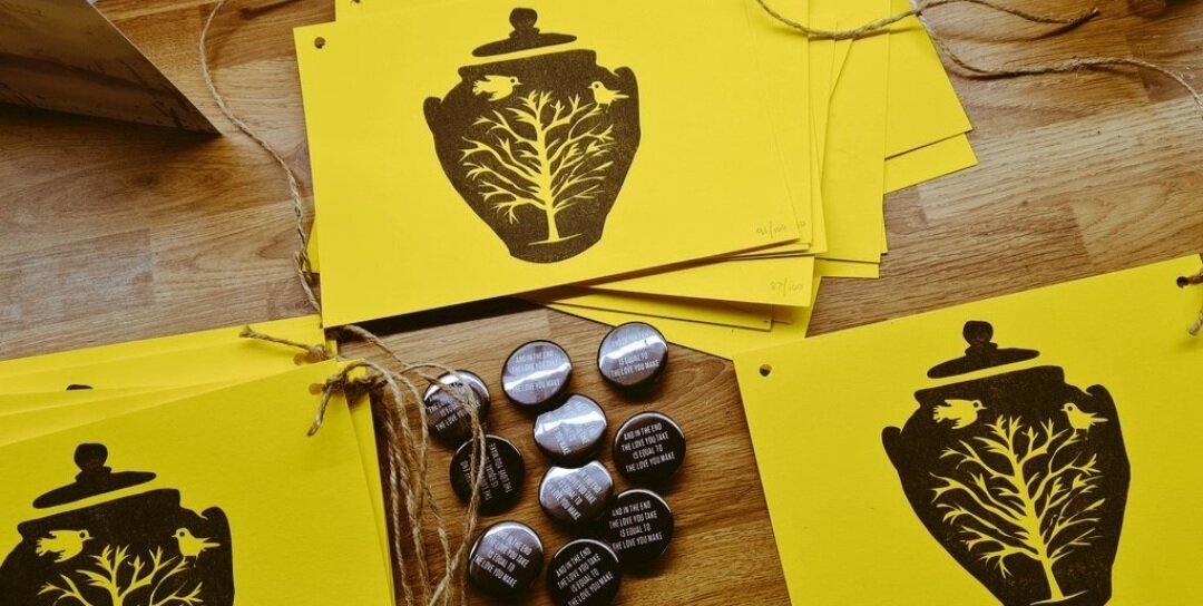 Yellow paper with a black vase design and buttons on a wooden table.