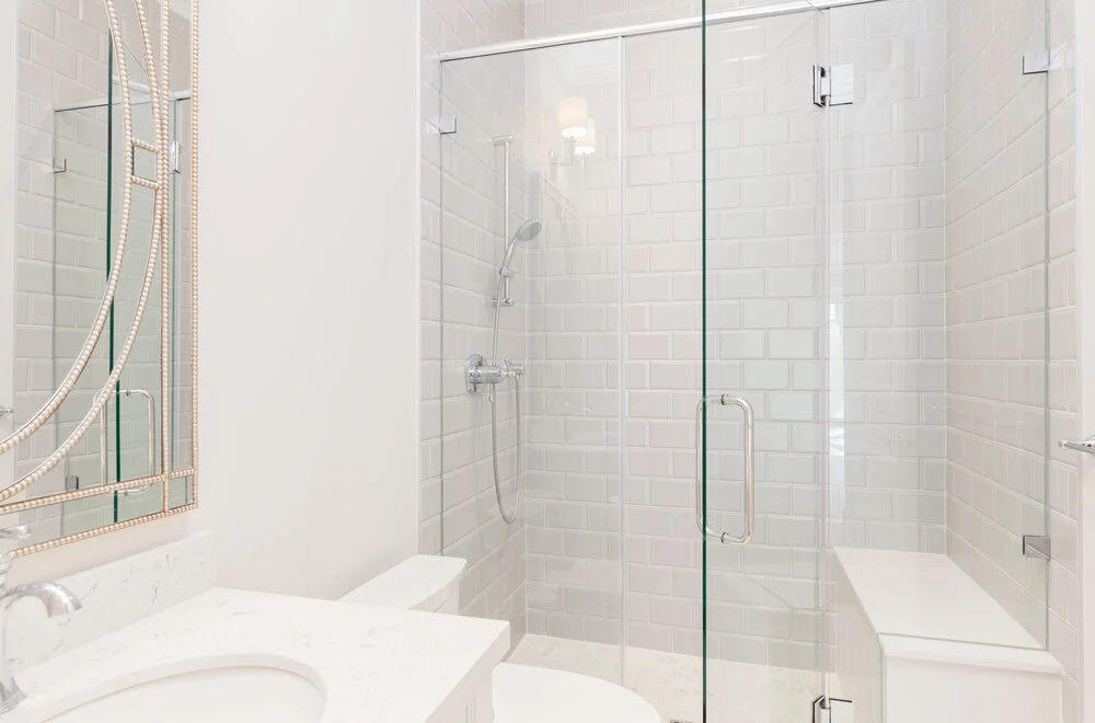 glass walk-in shower with white tiling
