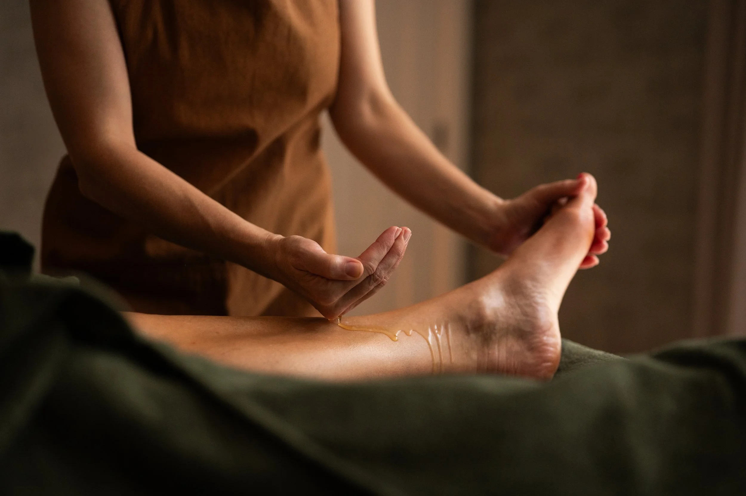 Warm herbal oil applied to the leg during an Abhyanga Ayurvedic massage