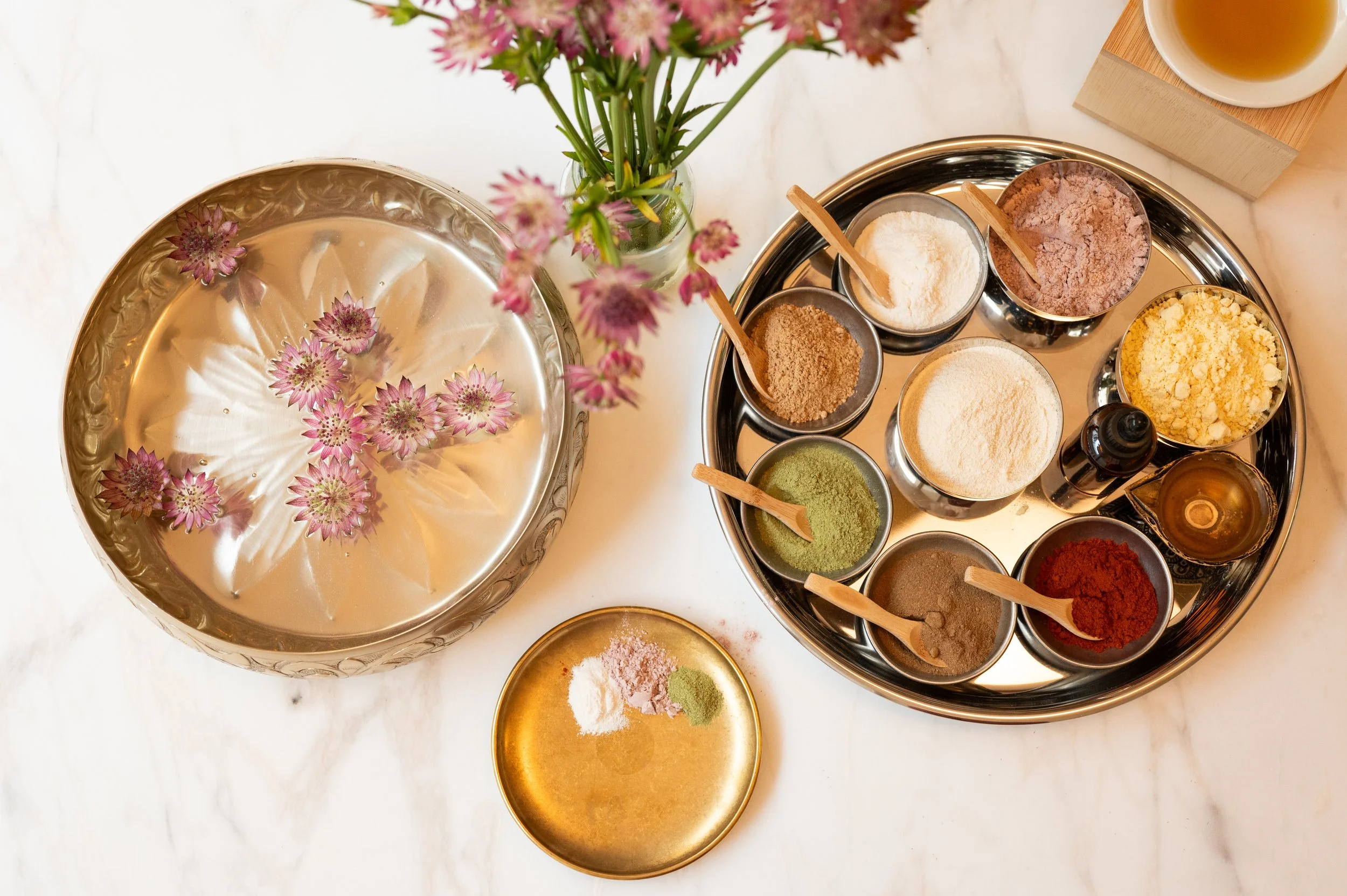 Ayurvedic herbal powders and oils arranged in brass bowls for treatment preparation