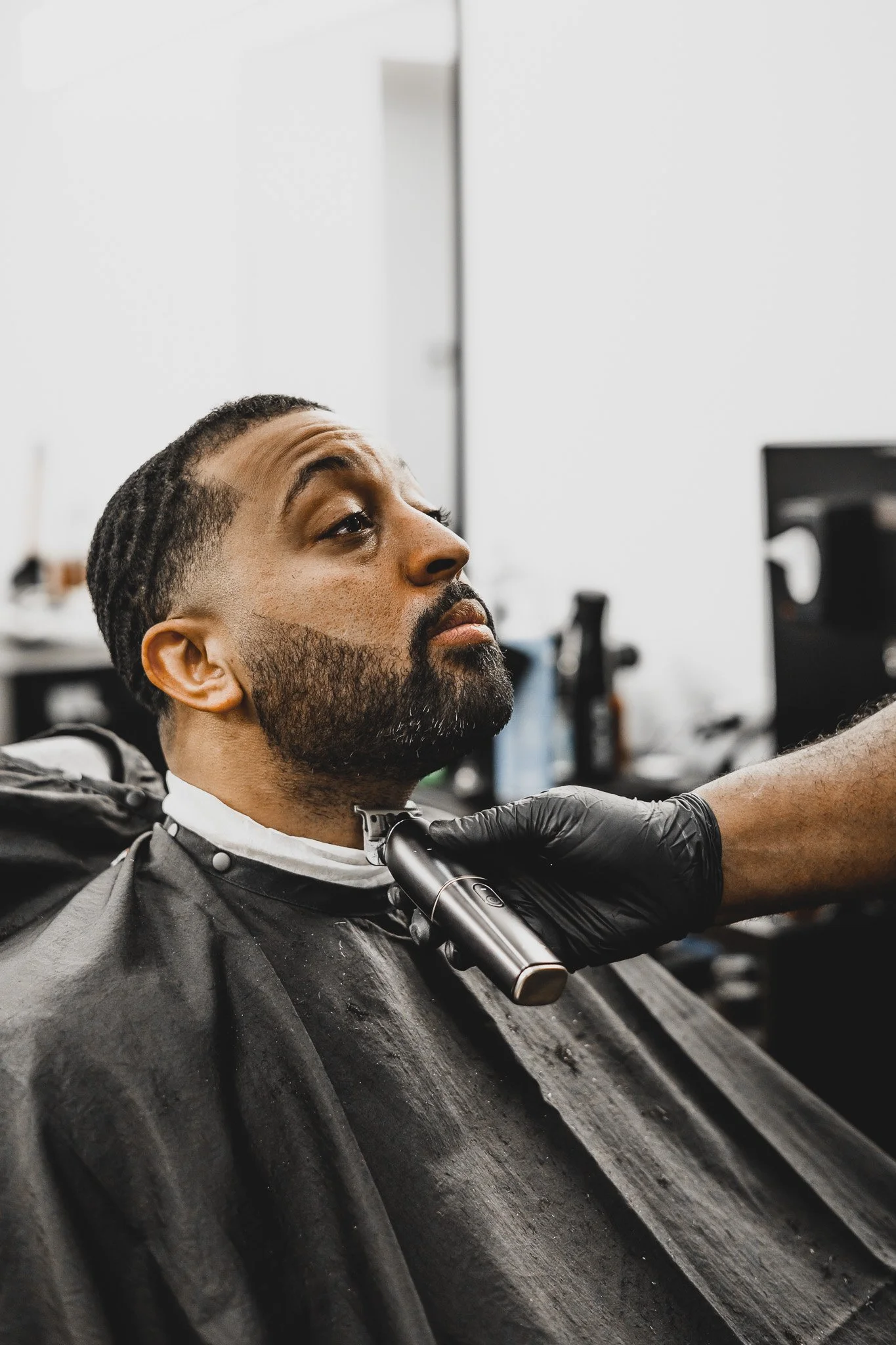 Man with dreadlocks and beard getting a haircut in a barber shop.