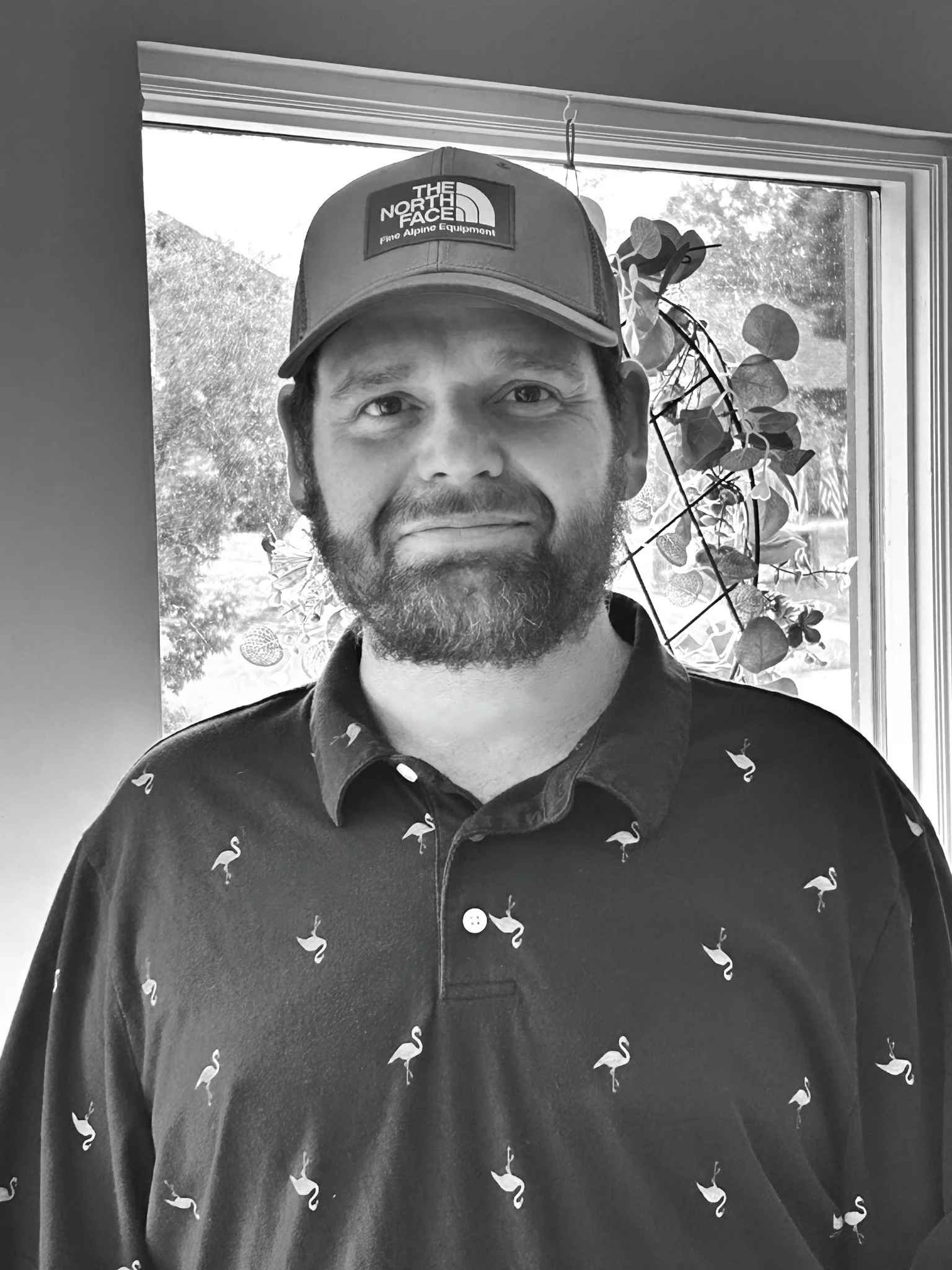 Smiling man with a beard weating a ball cap and polo shirt