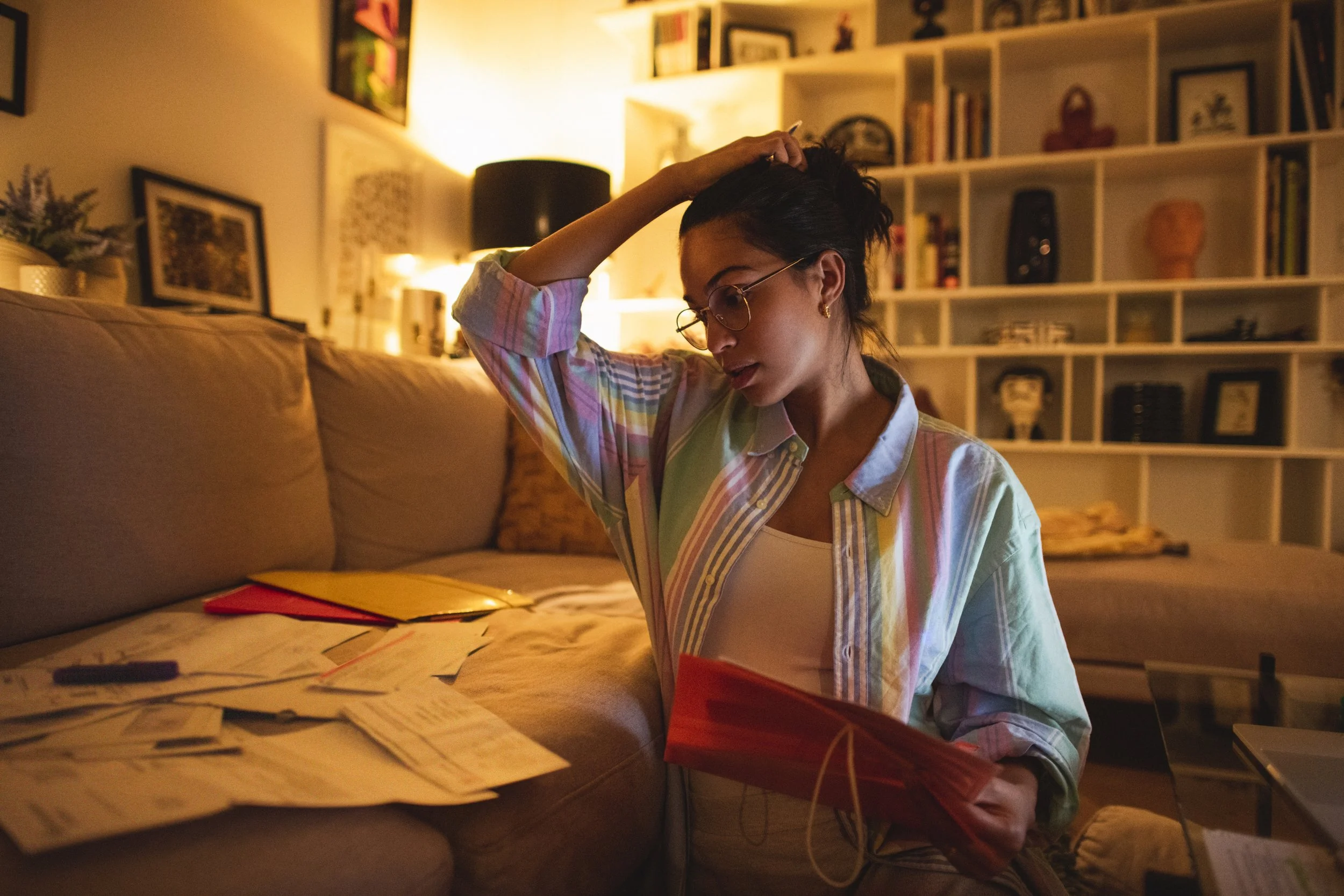 Woman in dimly lit room looking stressed while looking at calendar and bills, representing the financial and time burden of infertility treatment