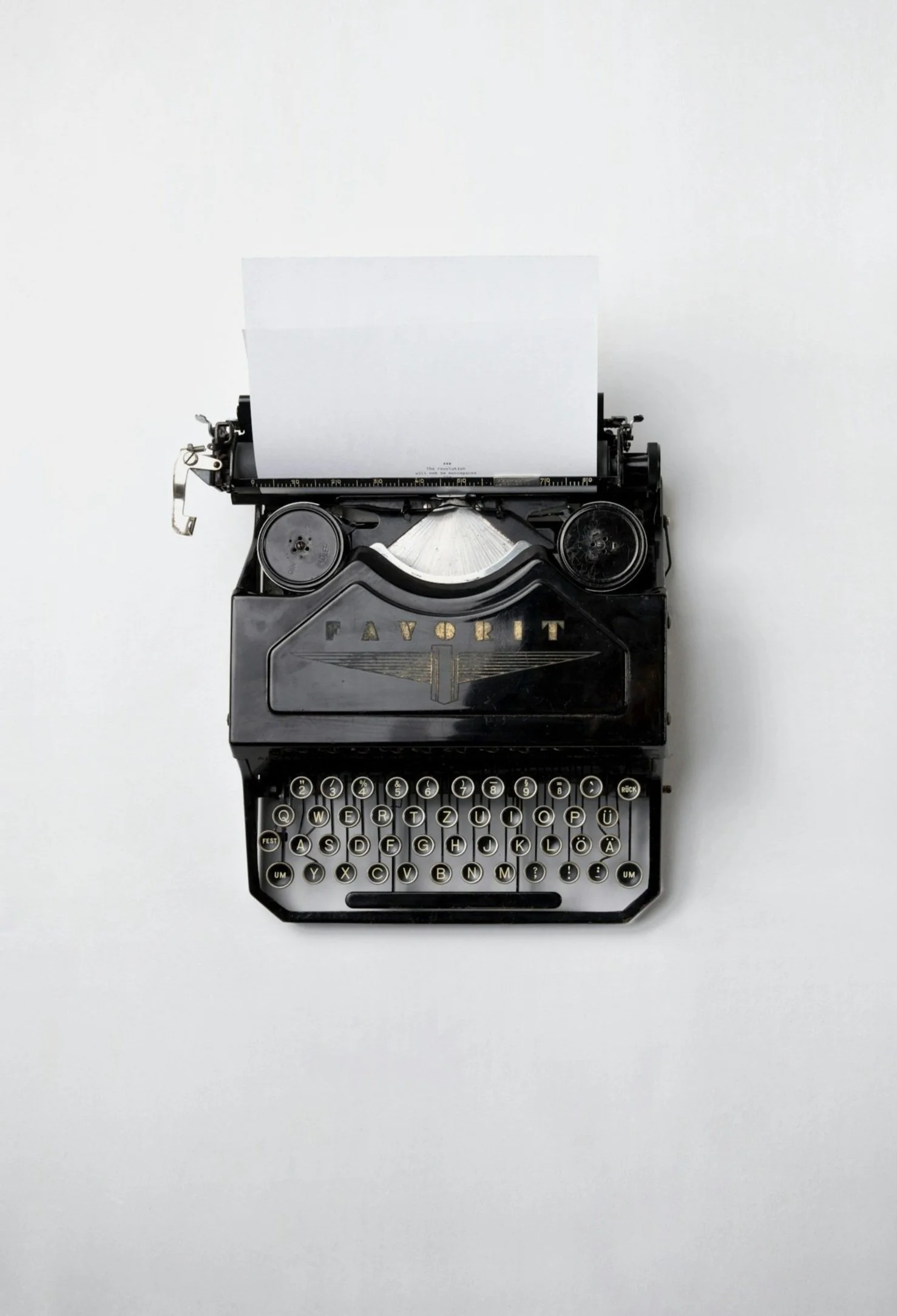 Black vintage typewriter with gold accent reading 'FAVORIT' on a white background.