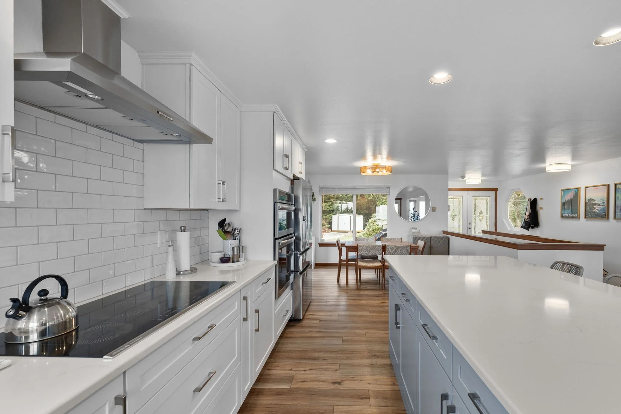 Modern kitchen remodel with large white island, quartz countertops, custom cabinetry, and open-concept living space.