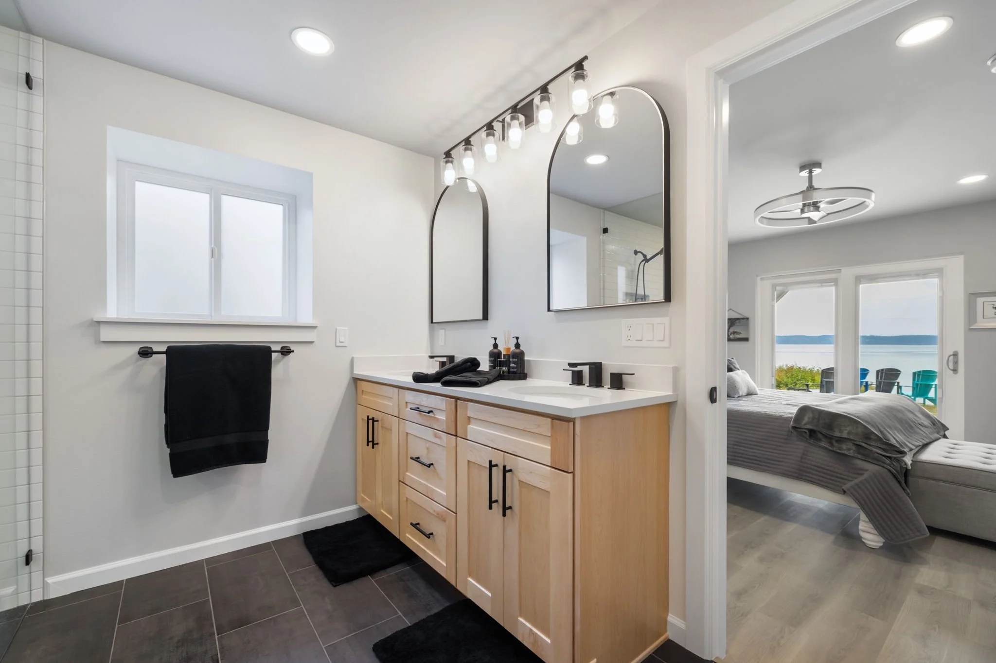 Lakebay bathroom with natural wood vanity, modern lighting and mirrors, and tile floors.