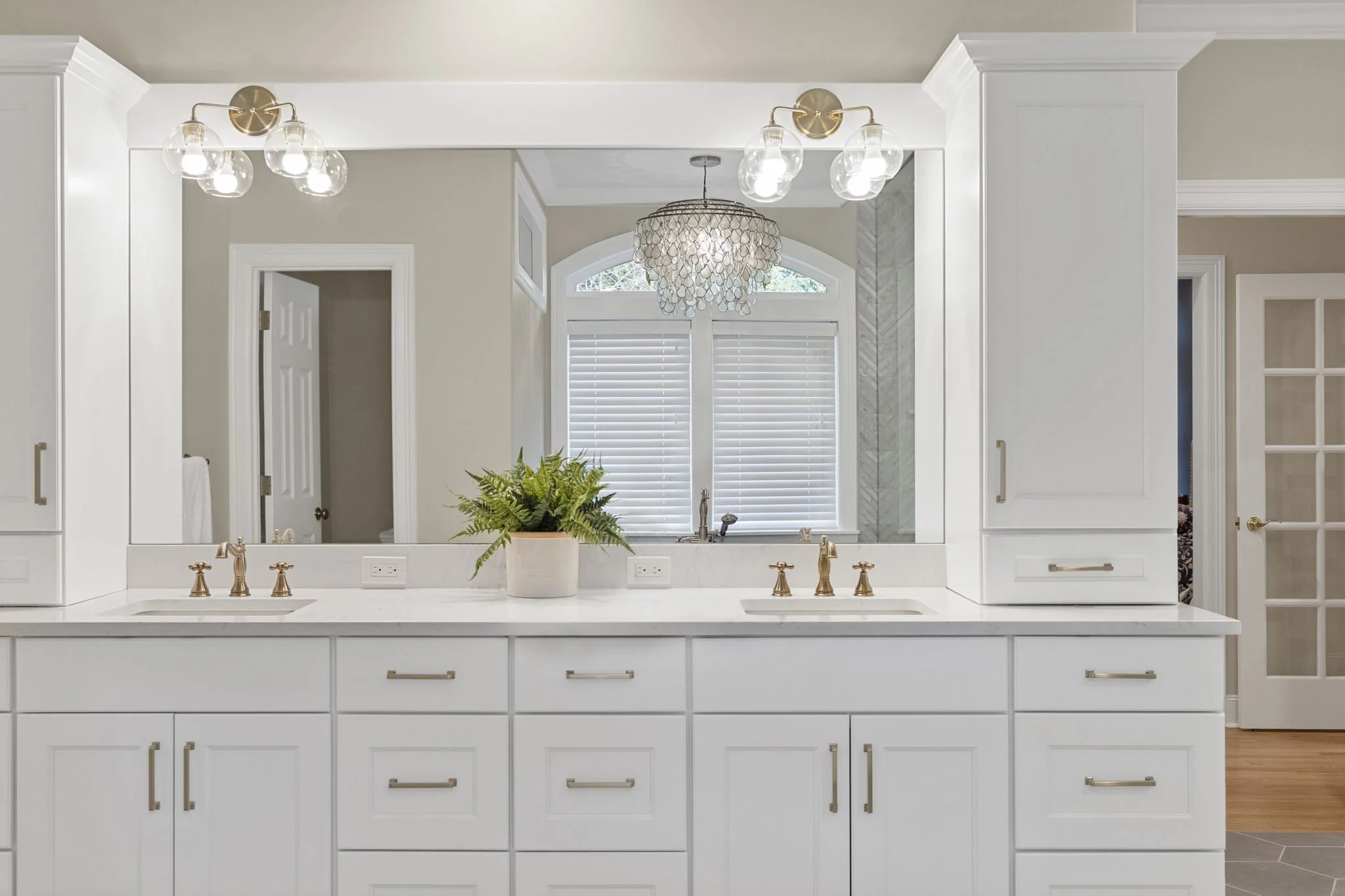 Upscale bathroom remodel in Gig Harbor, WA with white cabinets, white quartz countertops, and gold fixtures.