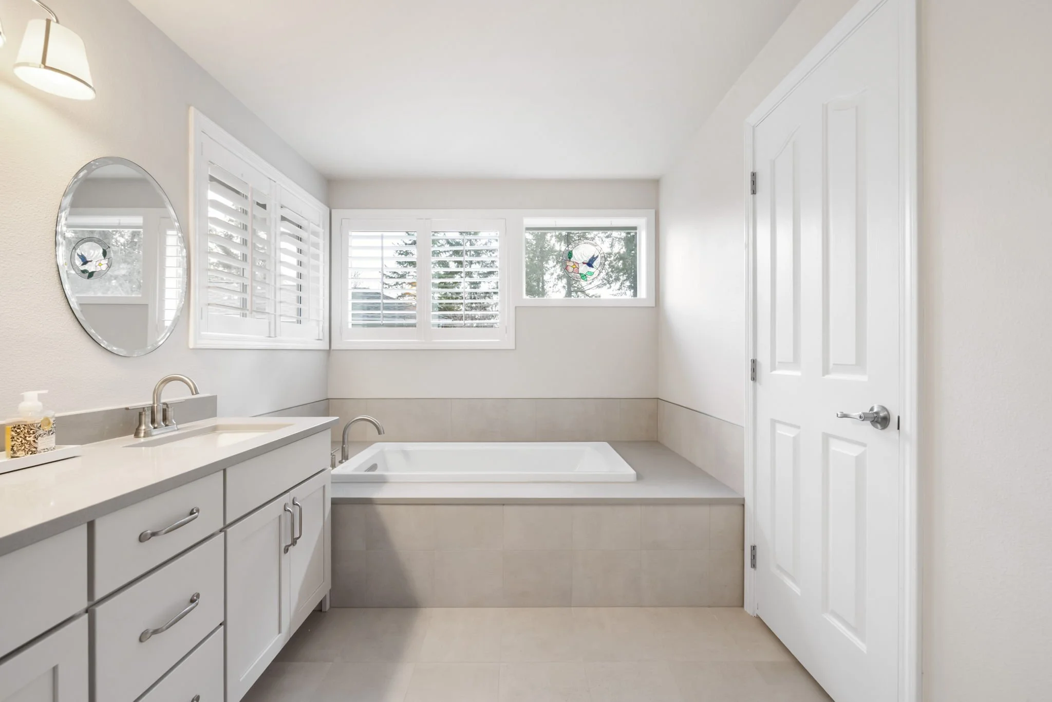 Primary bathroom remodel featuring soaking tub, custom tile surround, large windows, and bright modern finishes.