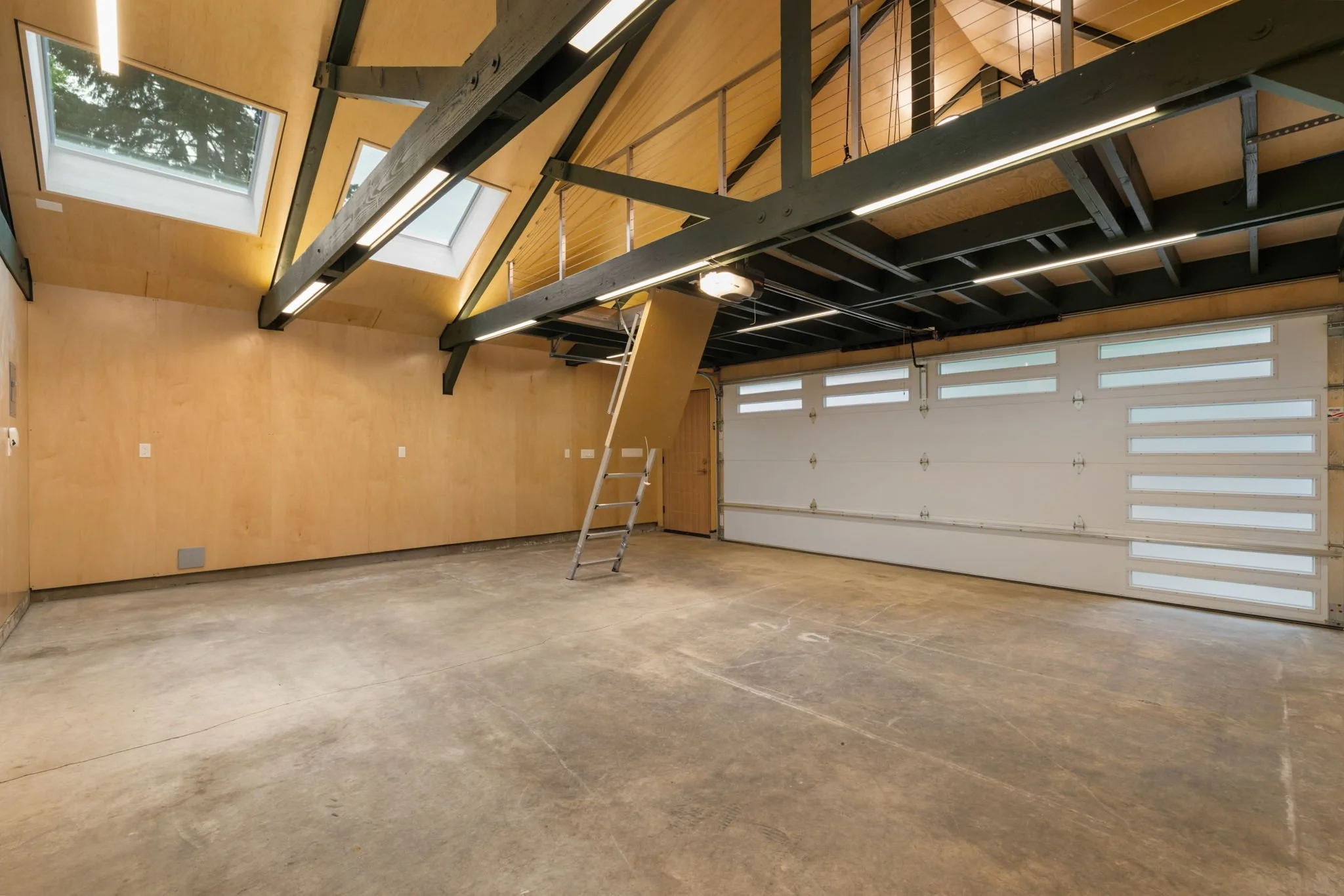 Garage remodel with exposed timber beams, high ceilings, storage loft access, and finished workshop space.