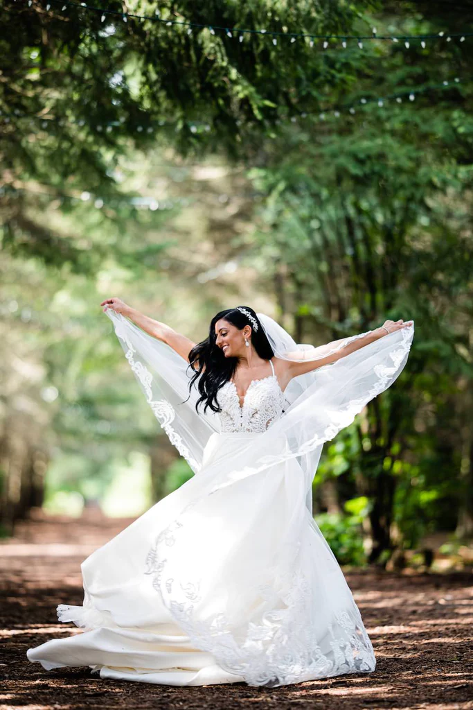 A bride shows off her ballgown dress in a gorgeous outdoor pathway.