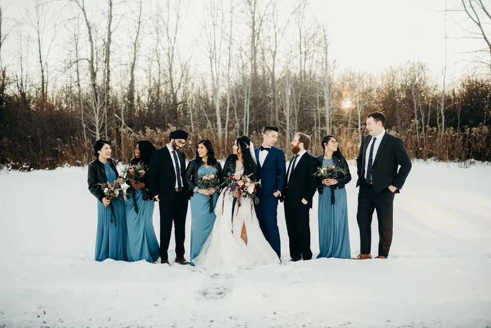  A wedding party stands outside and poses for a picture. 