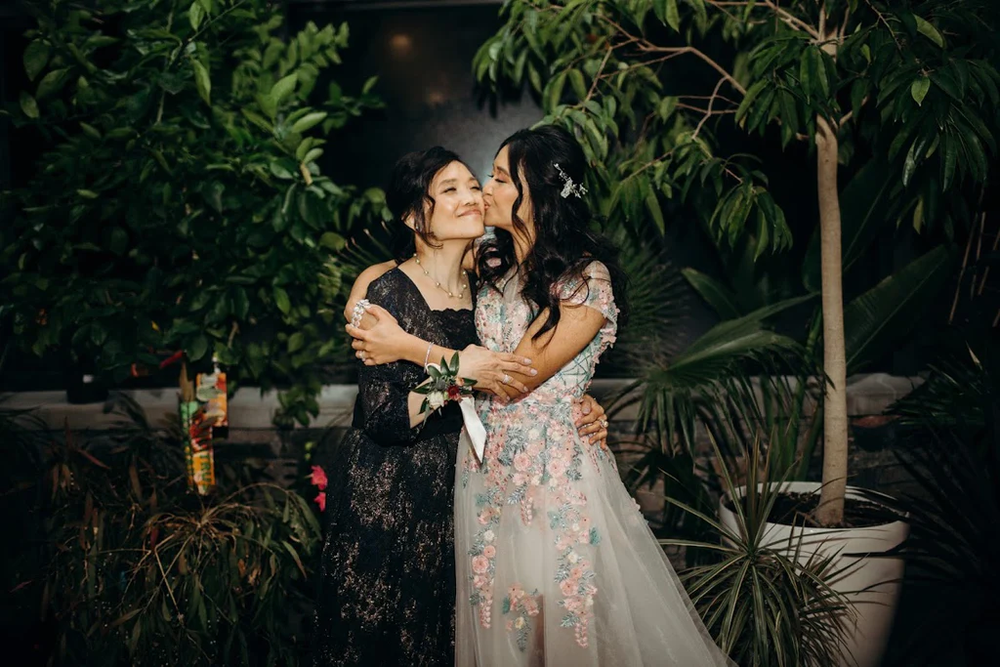  The bride gives her mom a kiss on the cheek. 