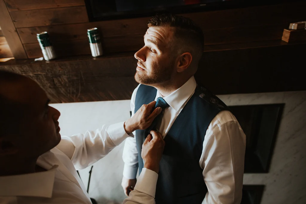  A groomsmen adjusts the grooms tie. 
