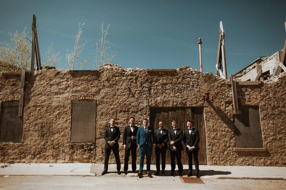  A groom and his groomsmen pose for a photo outside Elora Mill. 