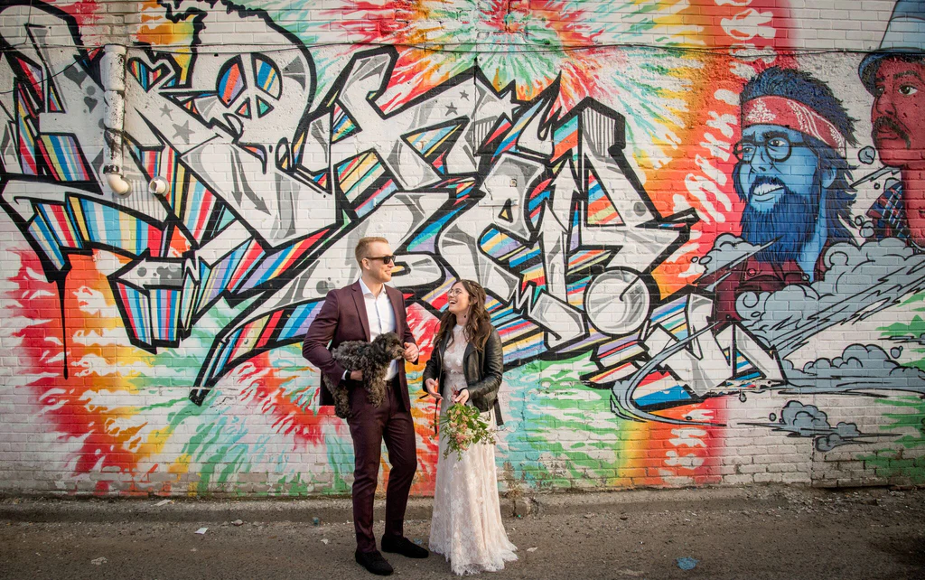 Toronto newlyweds standing in front of beautiful graffiti in an alley off Queen West in Toronto.