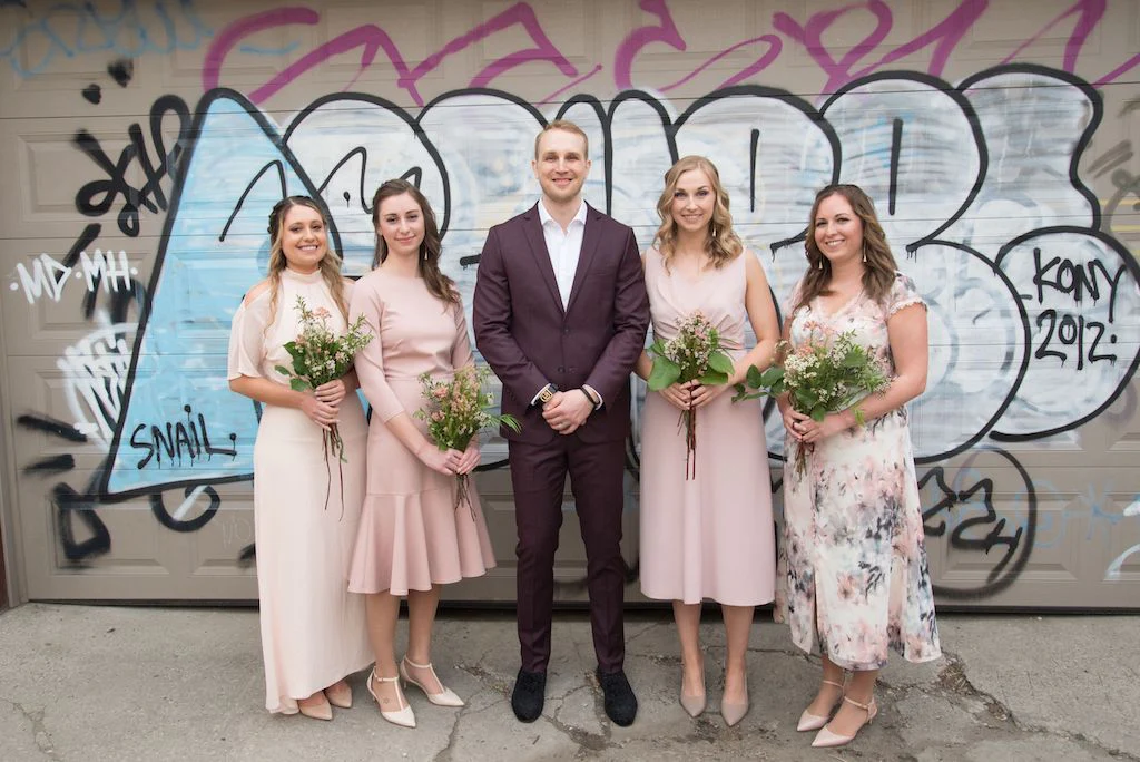The bridesmaids pose for a photo with the groom.