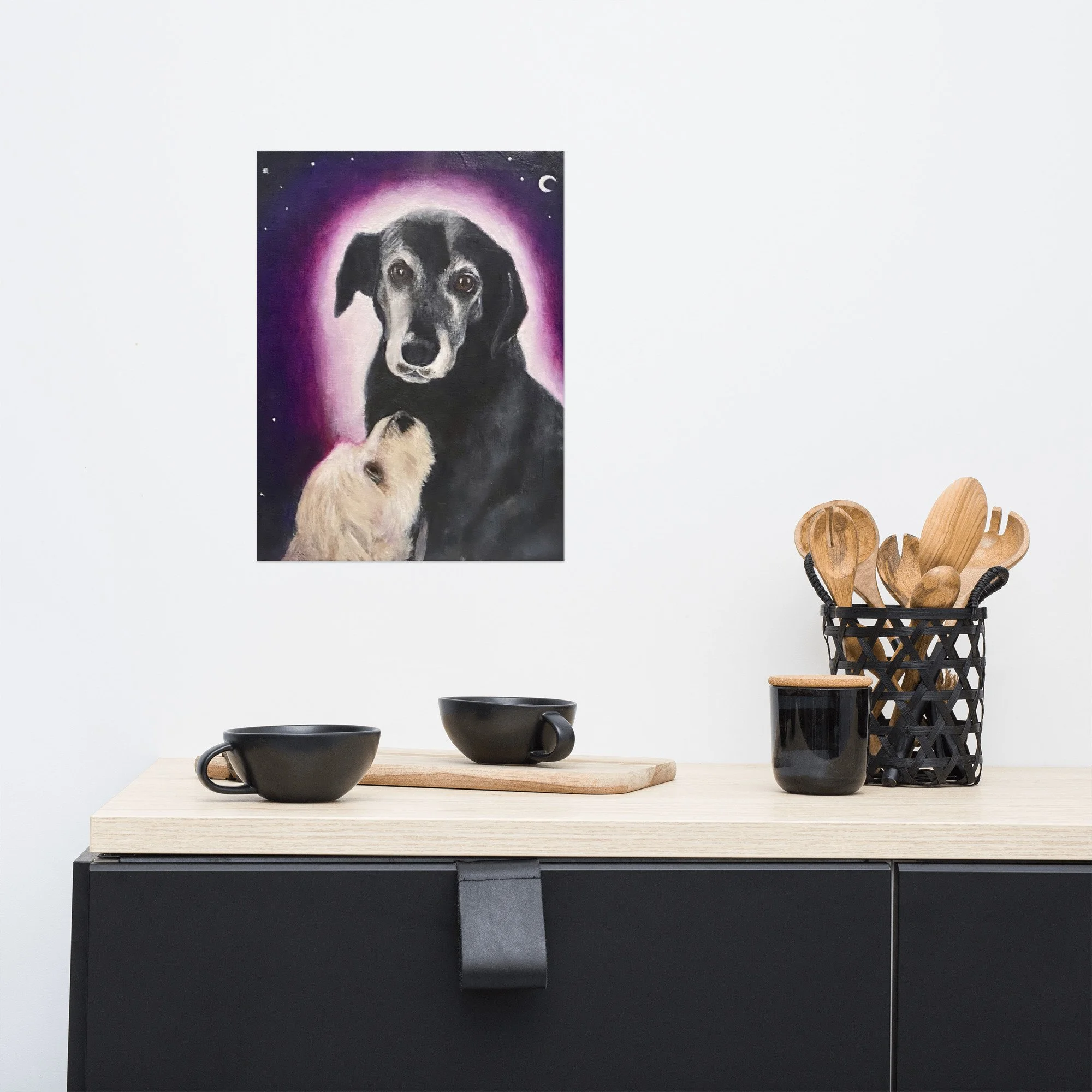 A modern kitchen with a fine art print of a dog portrait featuring an older black dog with a pink halo and a white dog looking up at them under a crescent moon by Diantha Boardman.