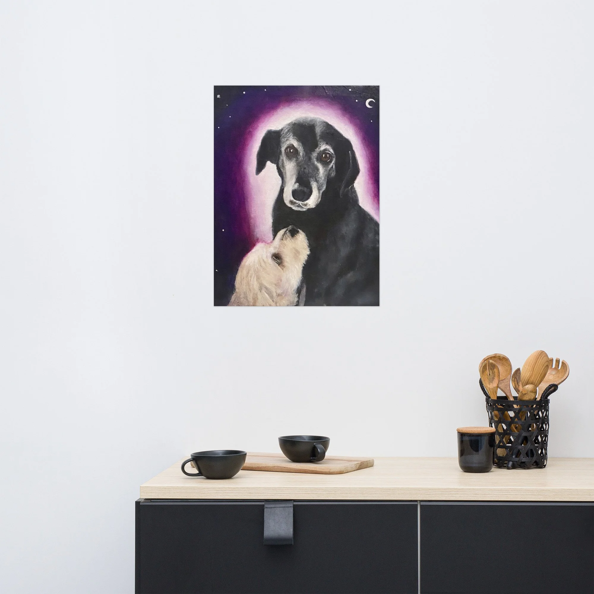 A modern kitchen with a fine art print of a dog portrait featuring an older black dog with a pink halo and a white dog looking up at them under a crescent moon by Diantha Boardman.