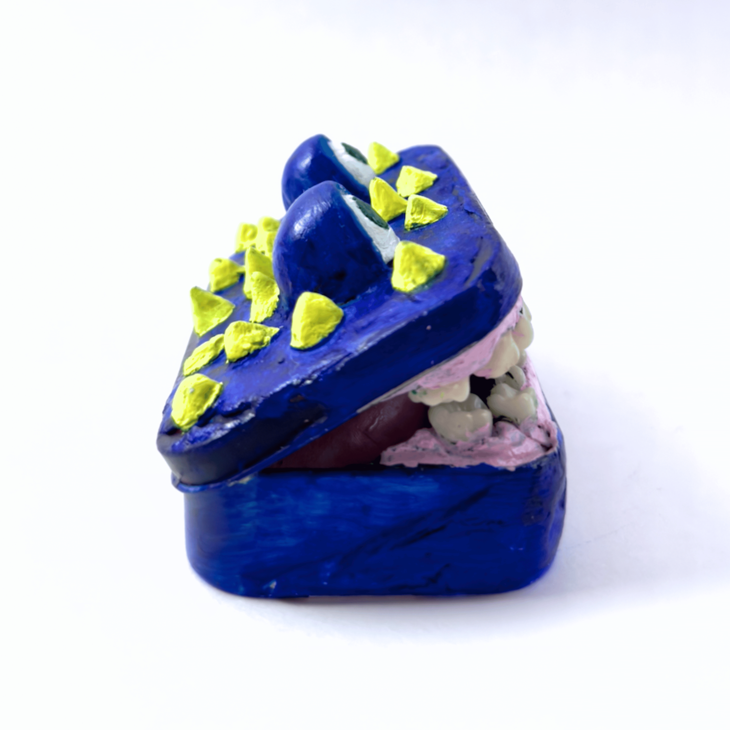 Side view of an original mixed media sculpture of a toothy monster inside a classic Altoid tin by Diantha Boardman.