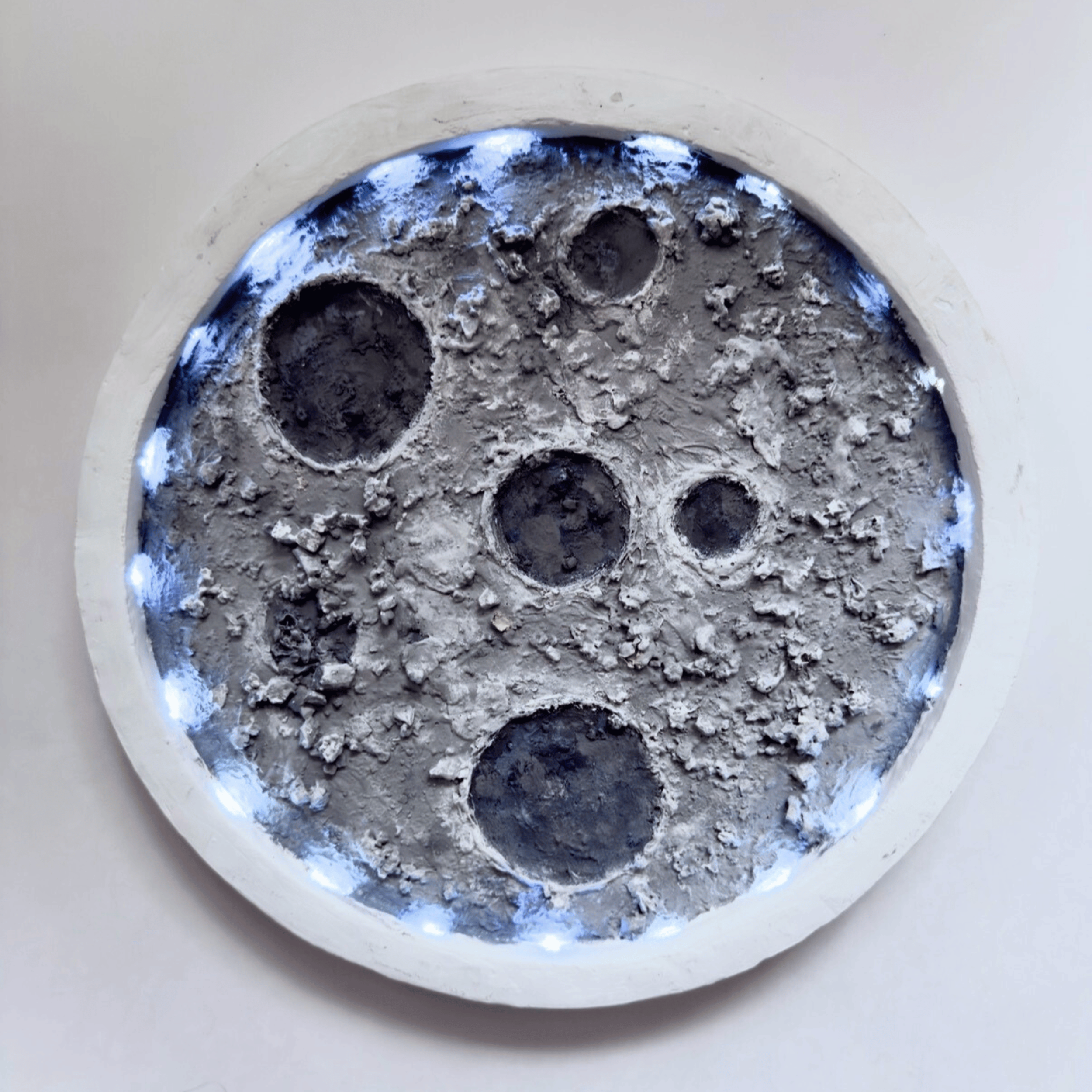 Original circular 3D moon sculpture with heavy gray texture and crater details by Diantha Boardman.