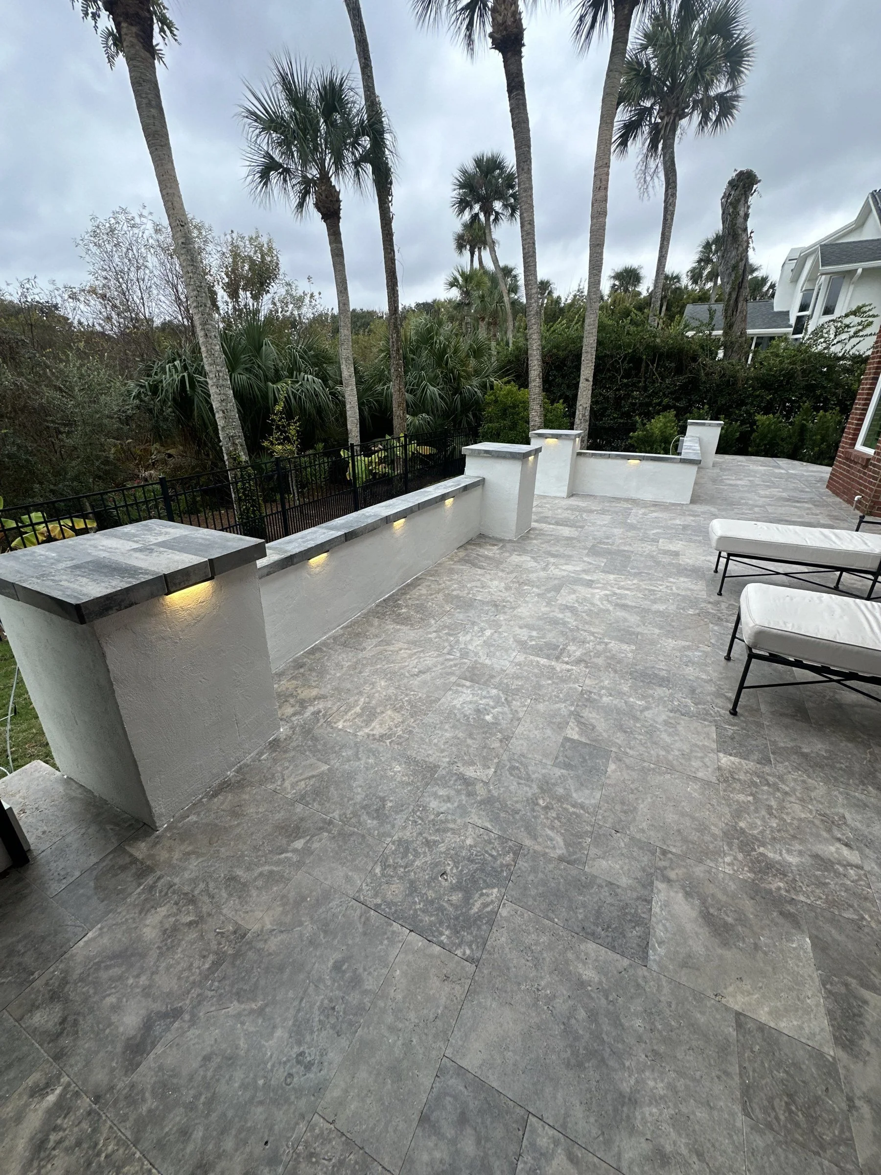 Travertine patio with stucco seating walls and columns in Ponte Vedra Beach