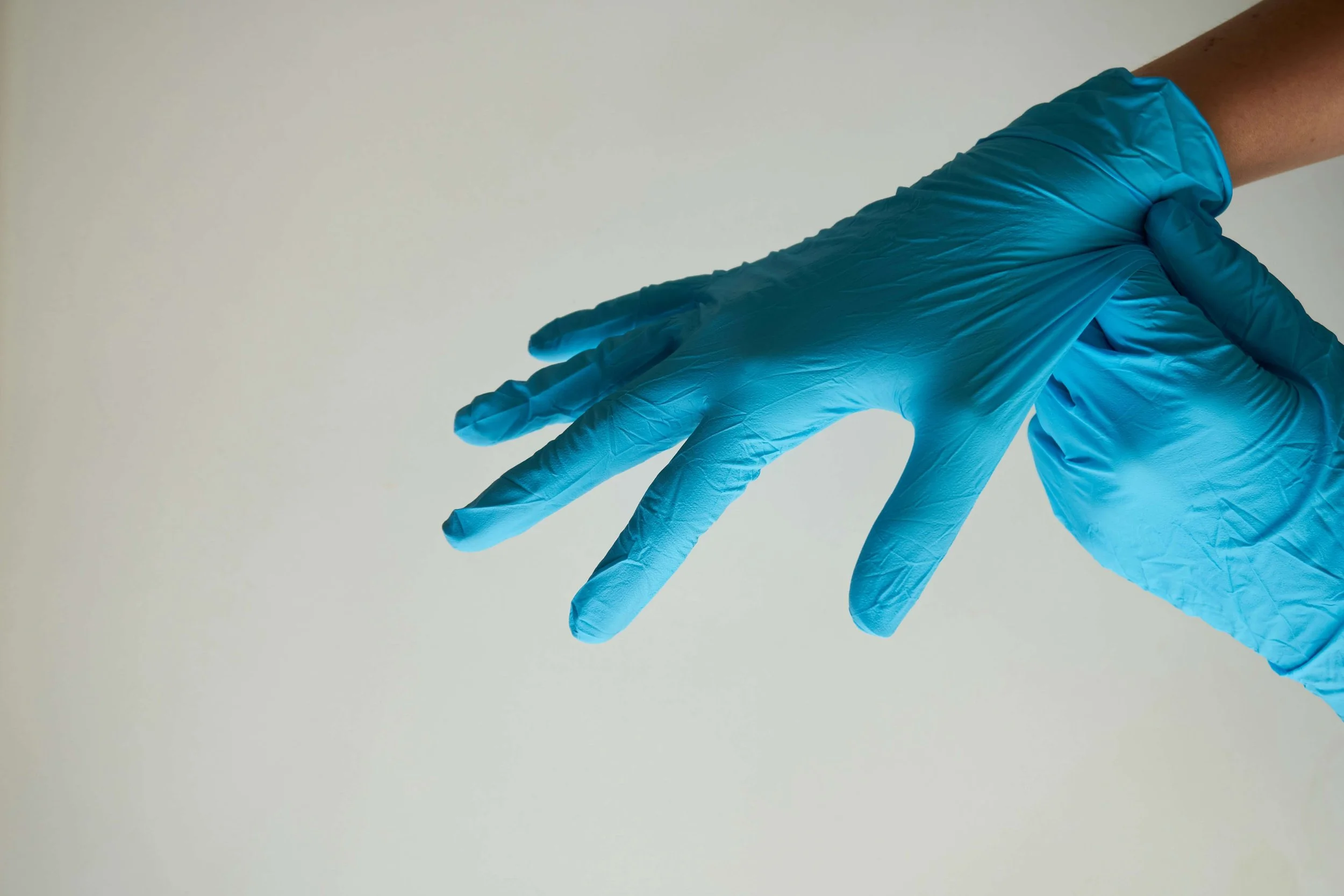close-up of hospital employee putting on blue latex gloves